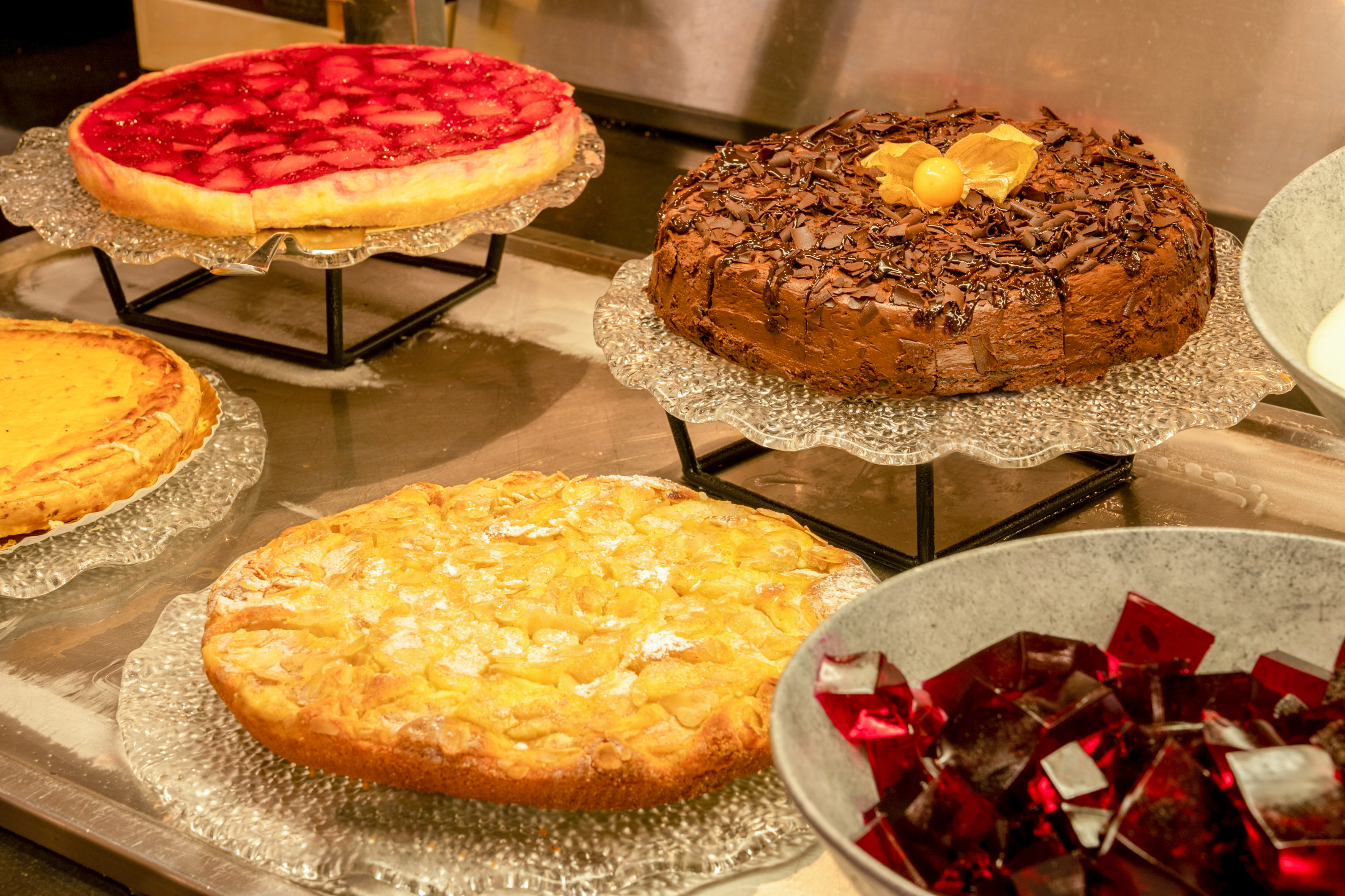 Dessert buffet with chocolate cake, strawberry tart, almond cake, and red jelly