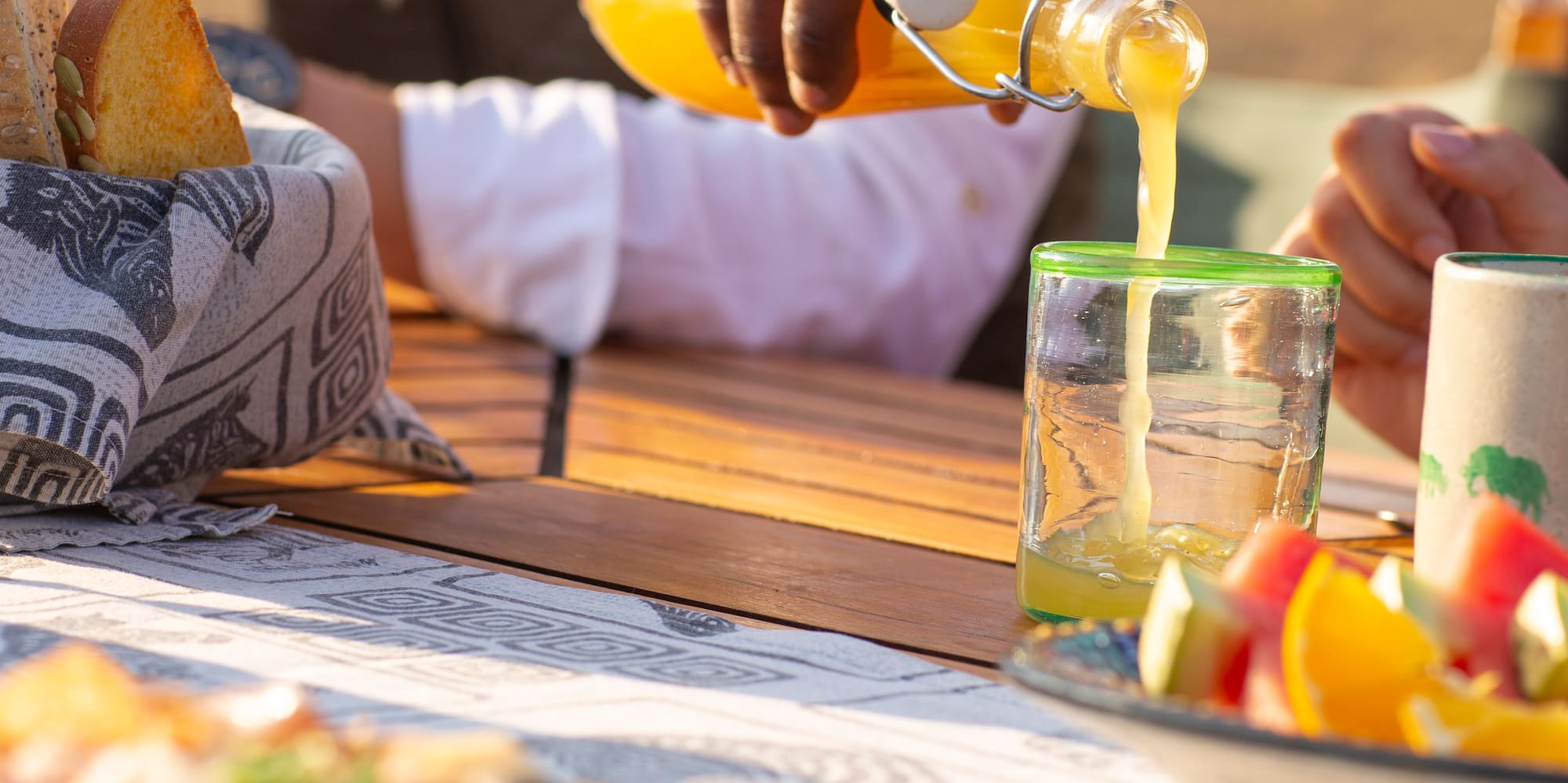 a person pouring orange juice into a glass