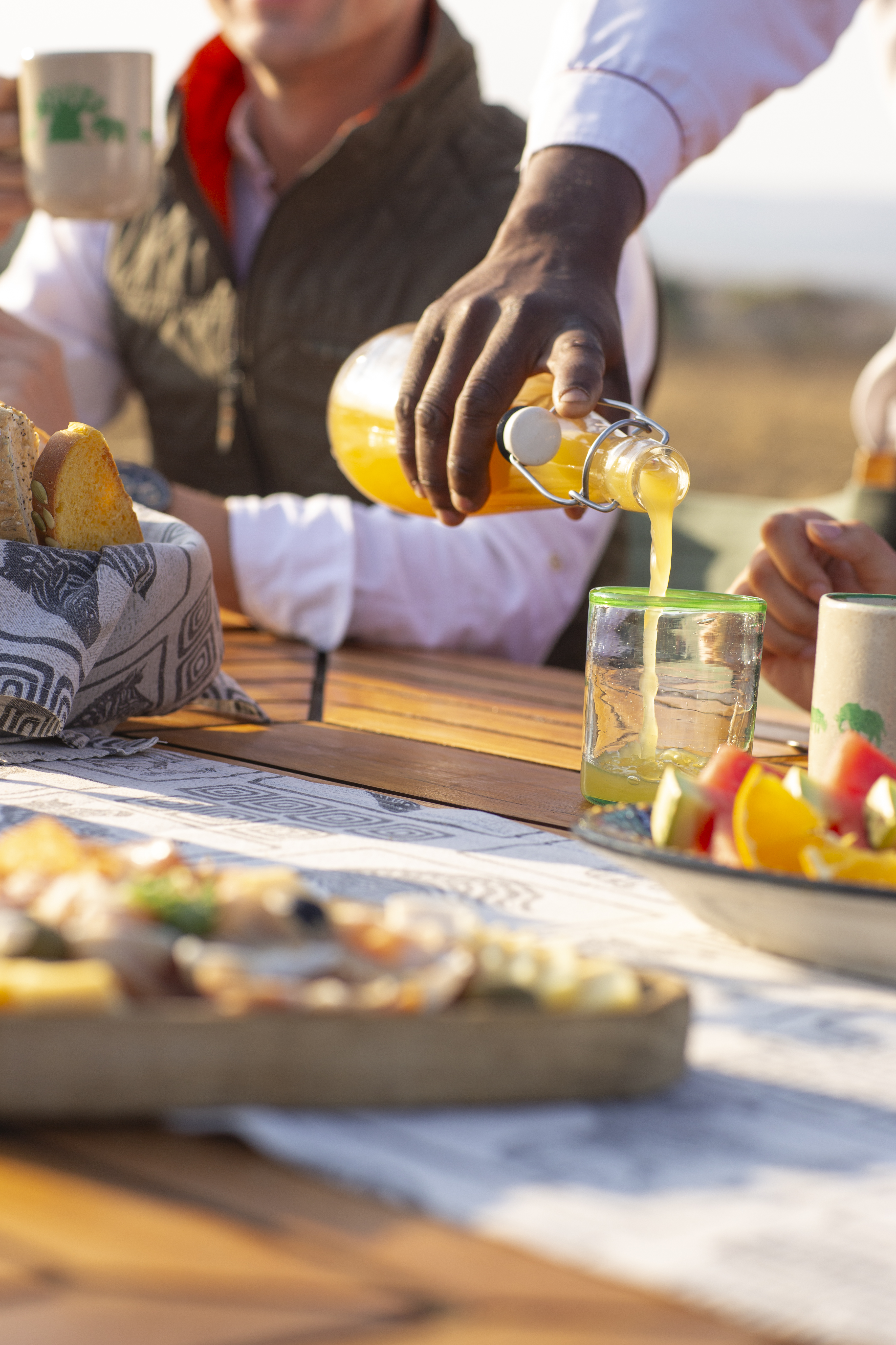 a person pouring orange juice into a glass