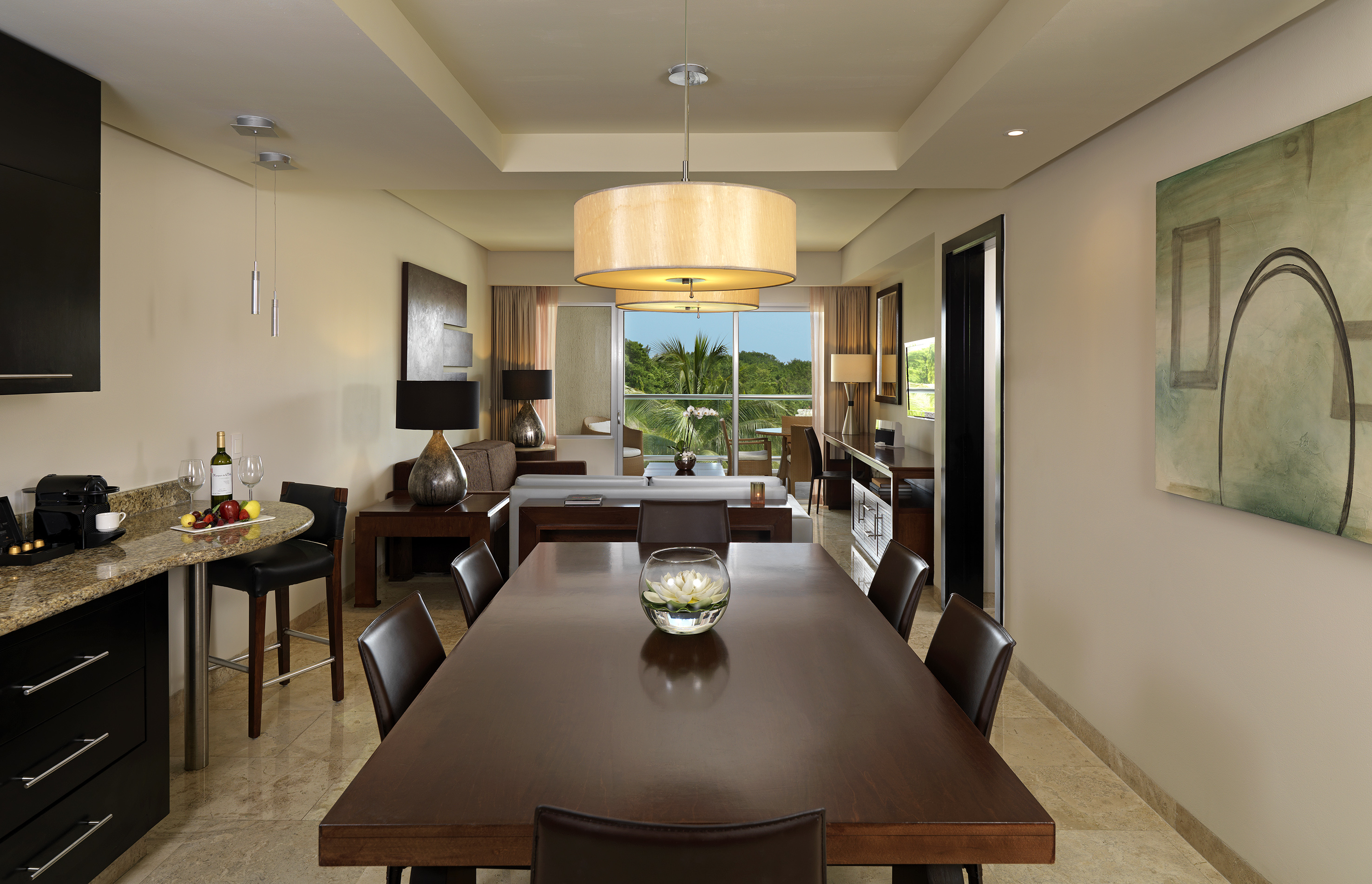 Elegant resort suite with wooden dining table and lush outdoor view.