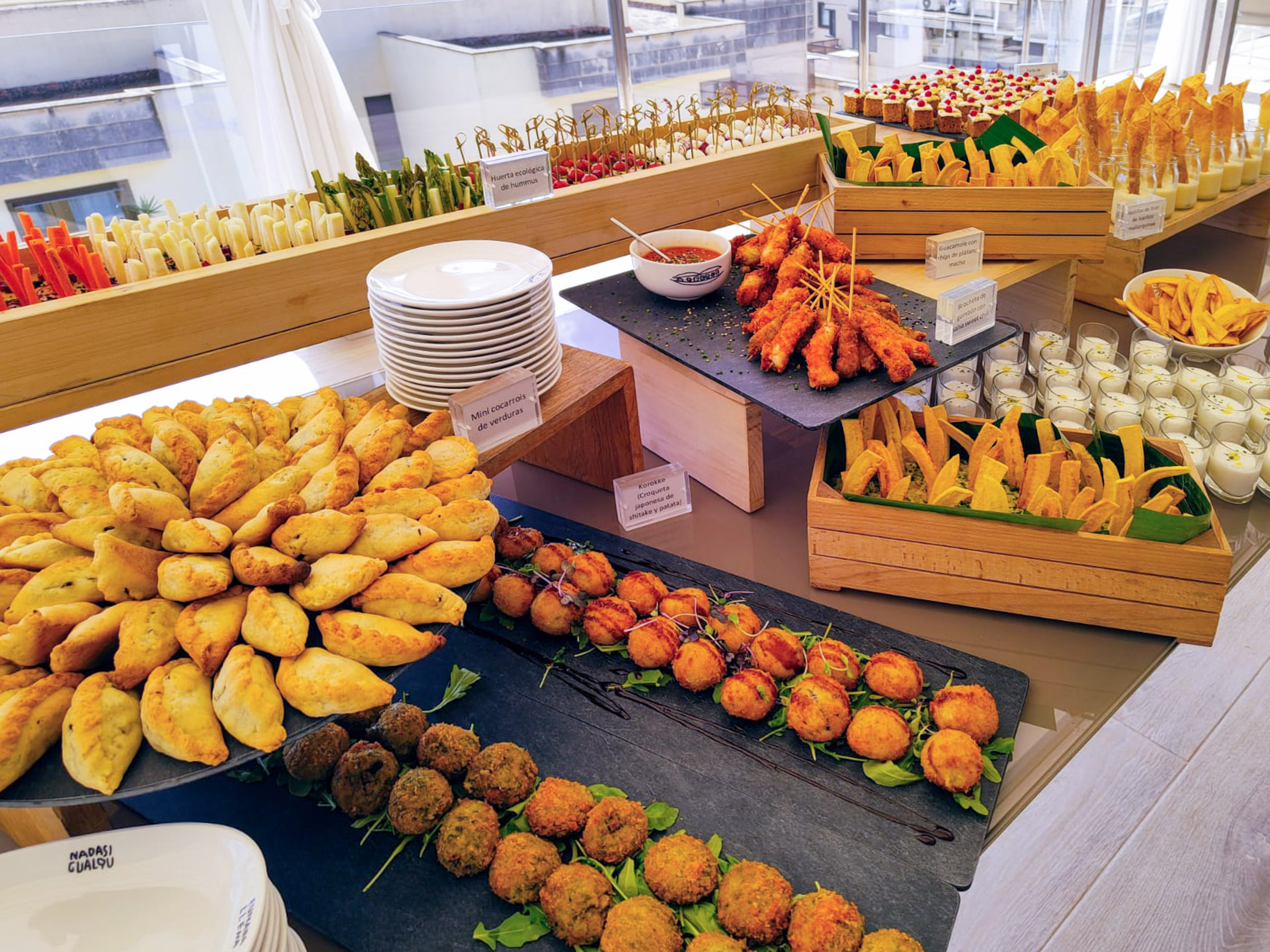 Gourmet buffet spread with empanadas, croquettes, skewers, and fresh vegetables.