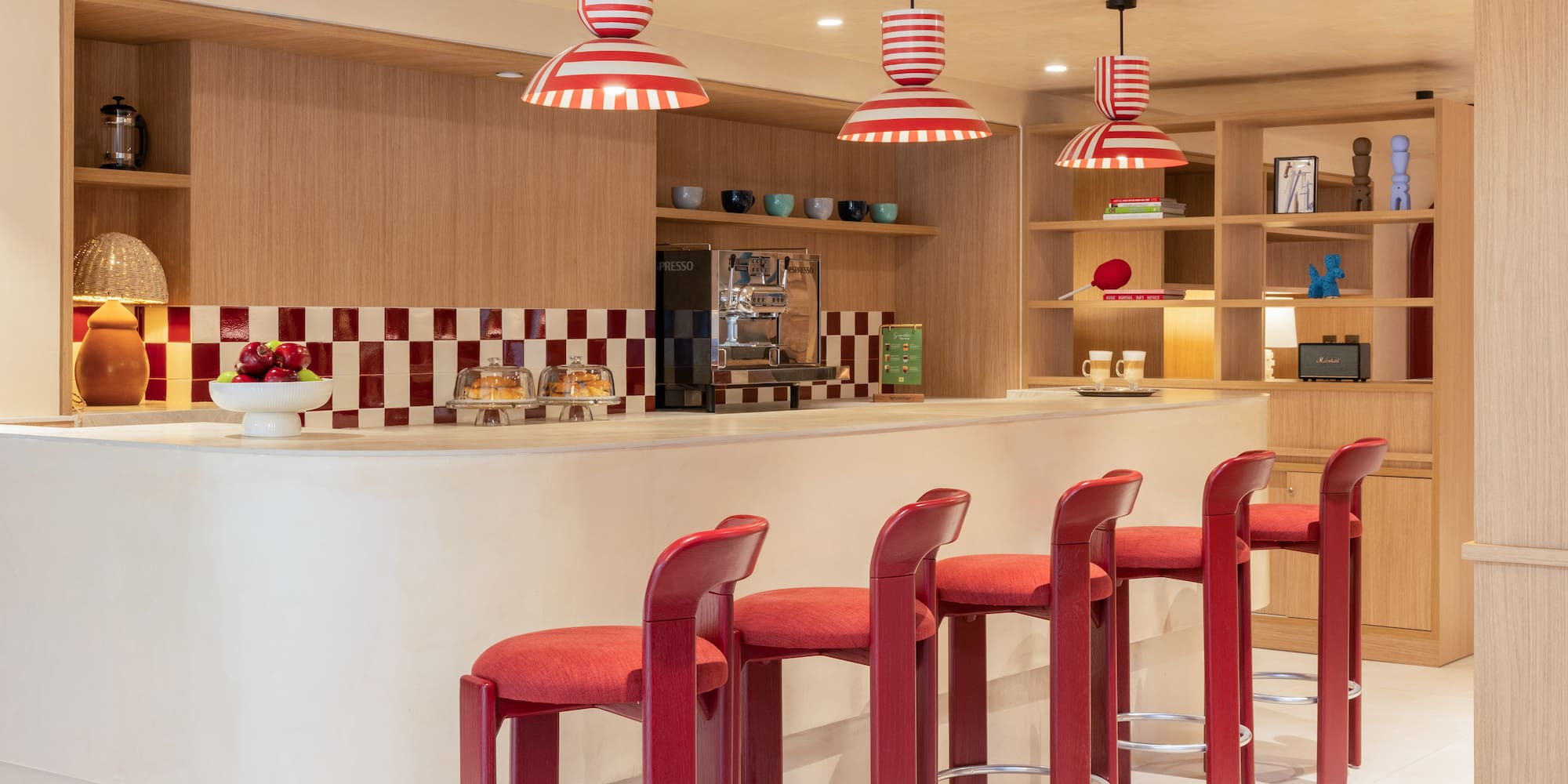 Modern bar with red stools, striped lights, and checkered backsplash.