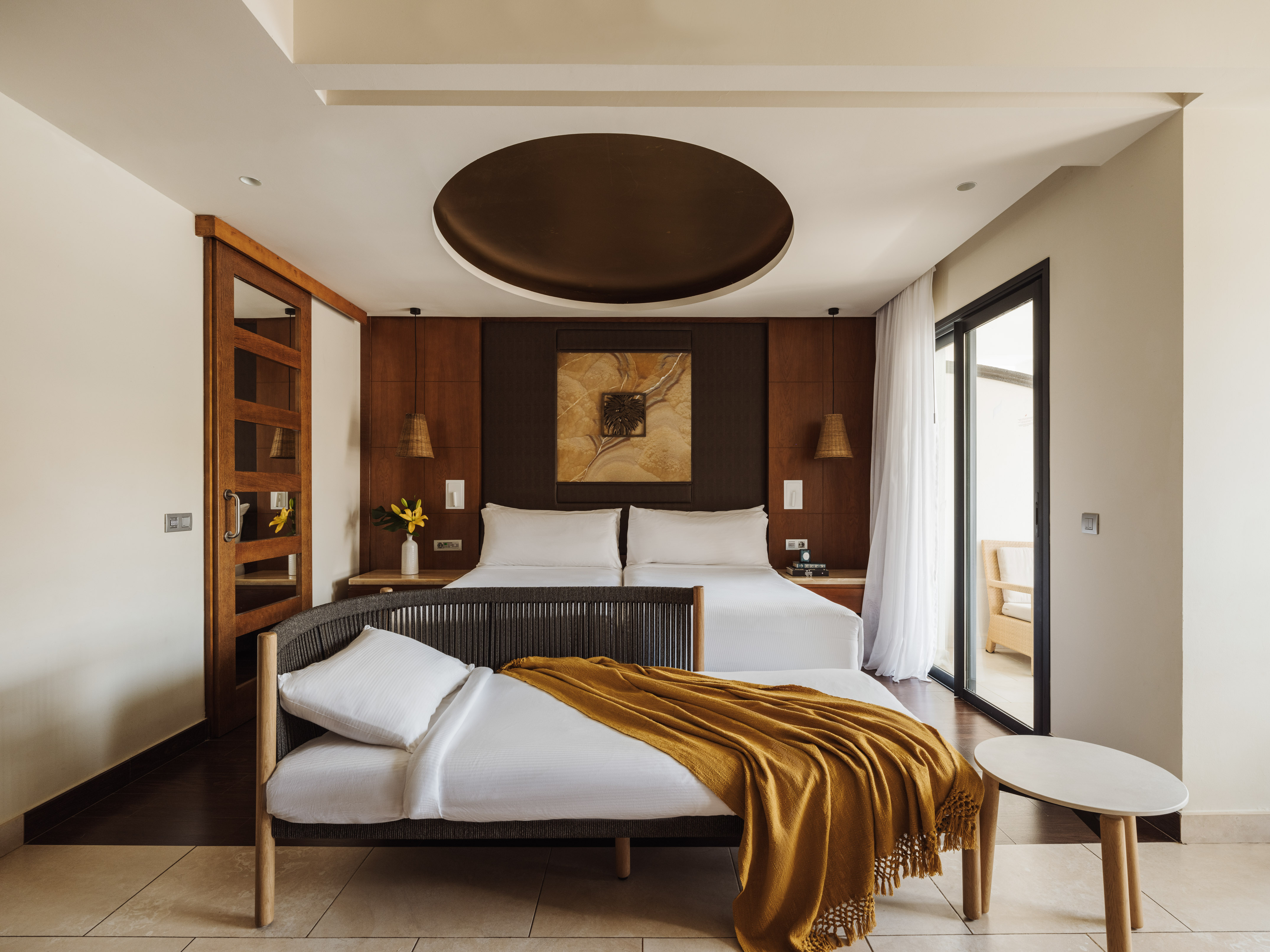 Modern hotel bedroom with king bed, wood paneling, and private balcony.