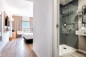 a bathroom with a glass shower and a bed