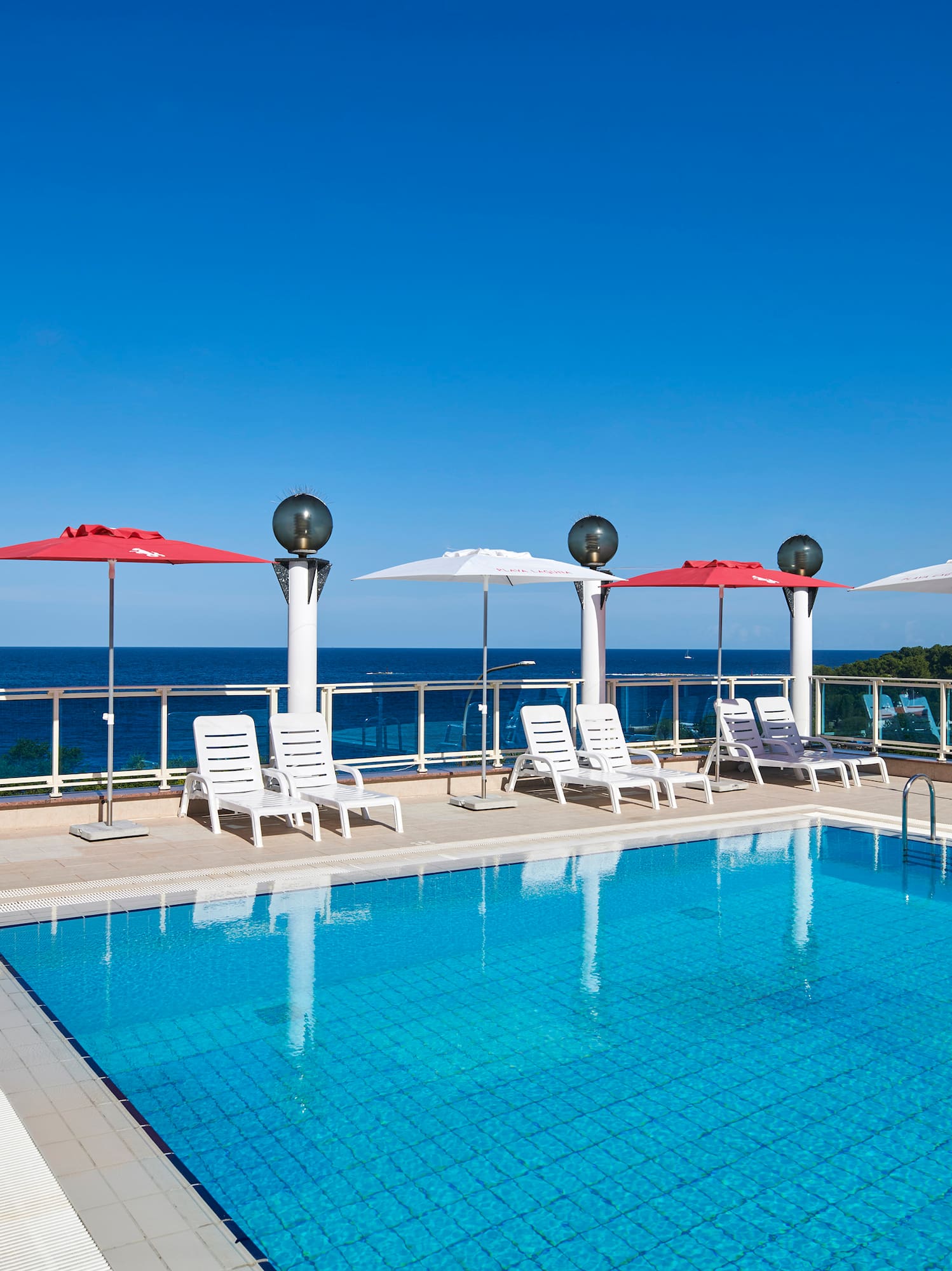 a pool with chairs and umbrellas by the water