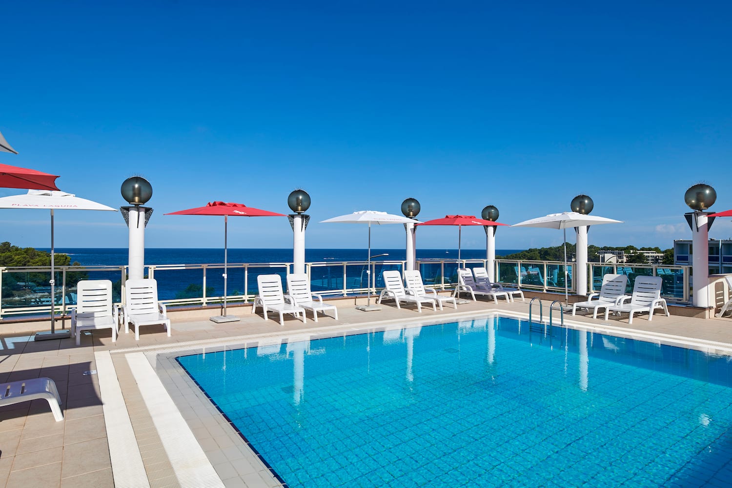 a pool with chairs and umbrellas by the water