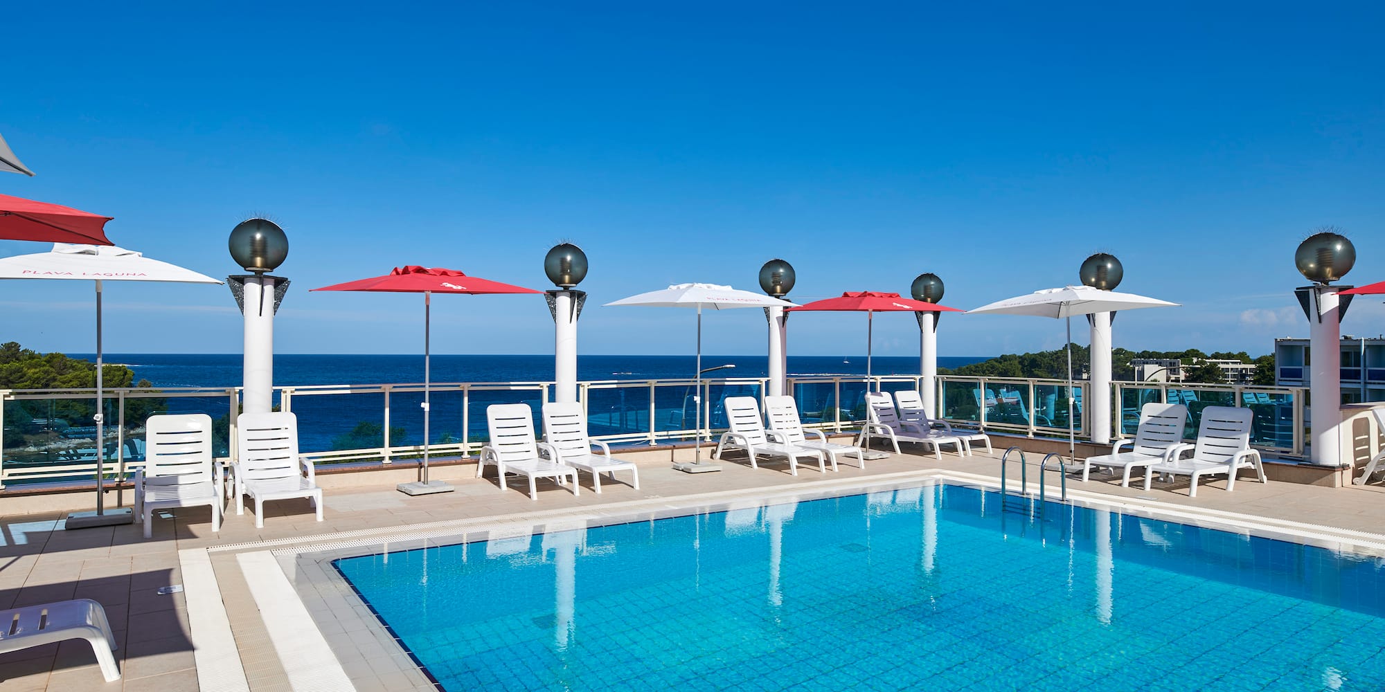 a pool with chairs and umbrellas by the water