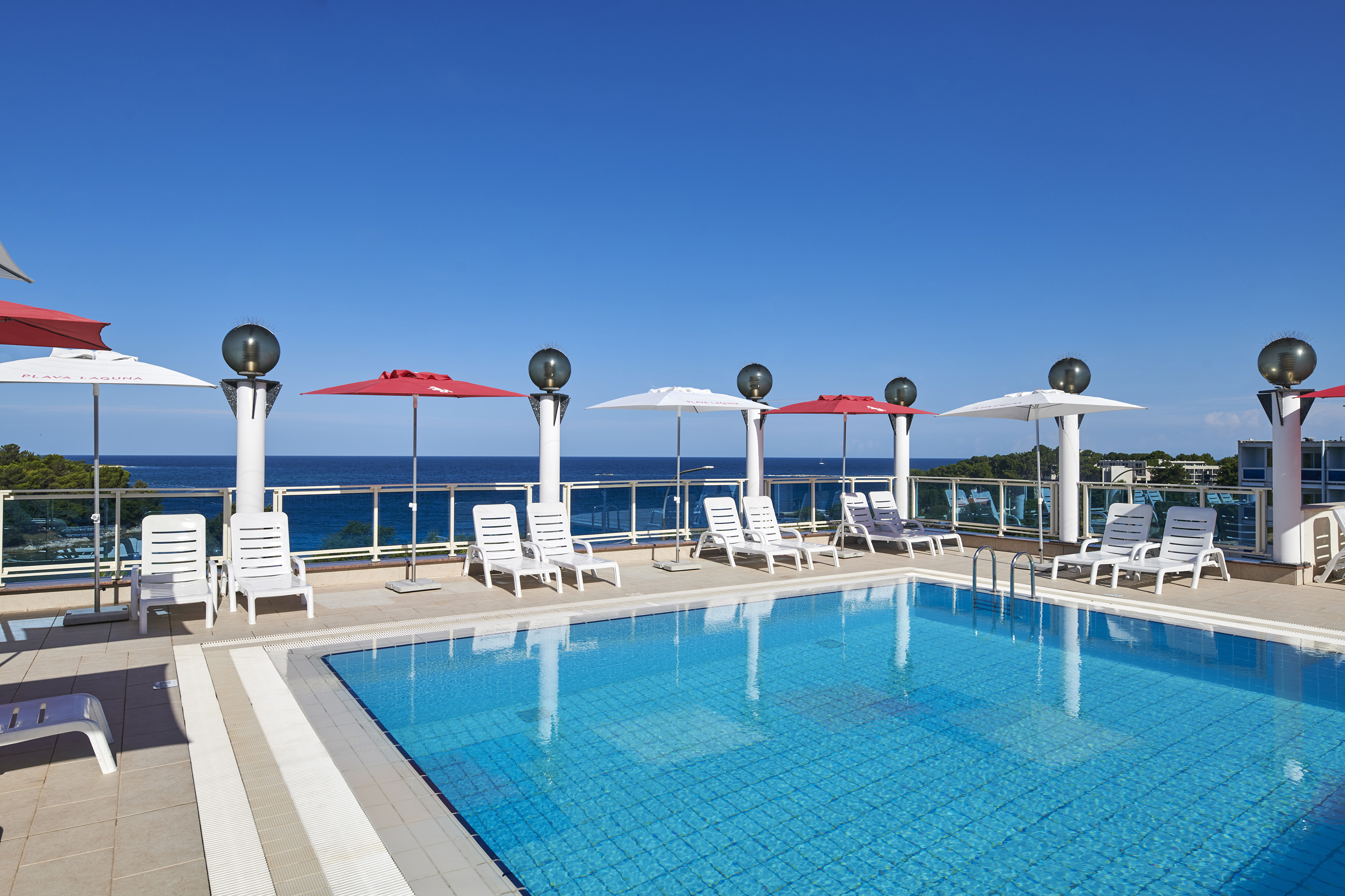 a pool with chairs and umbrellas by the water