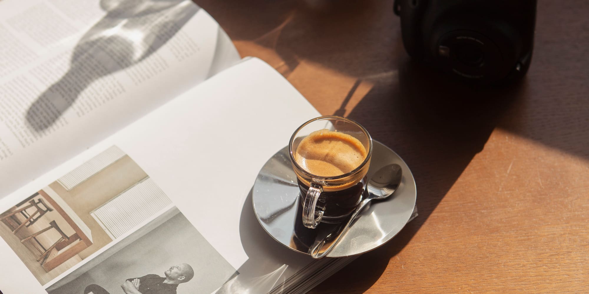 a cup of coffee on a saucer next to a book and glasses