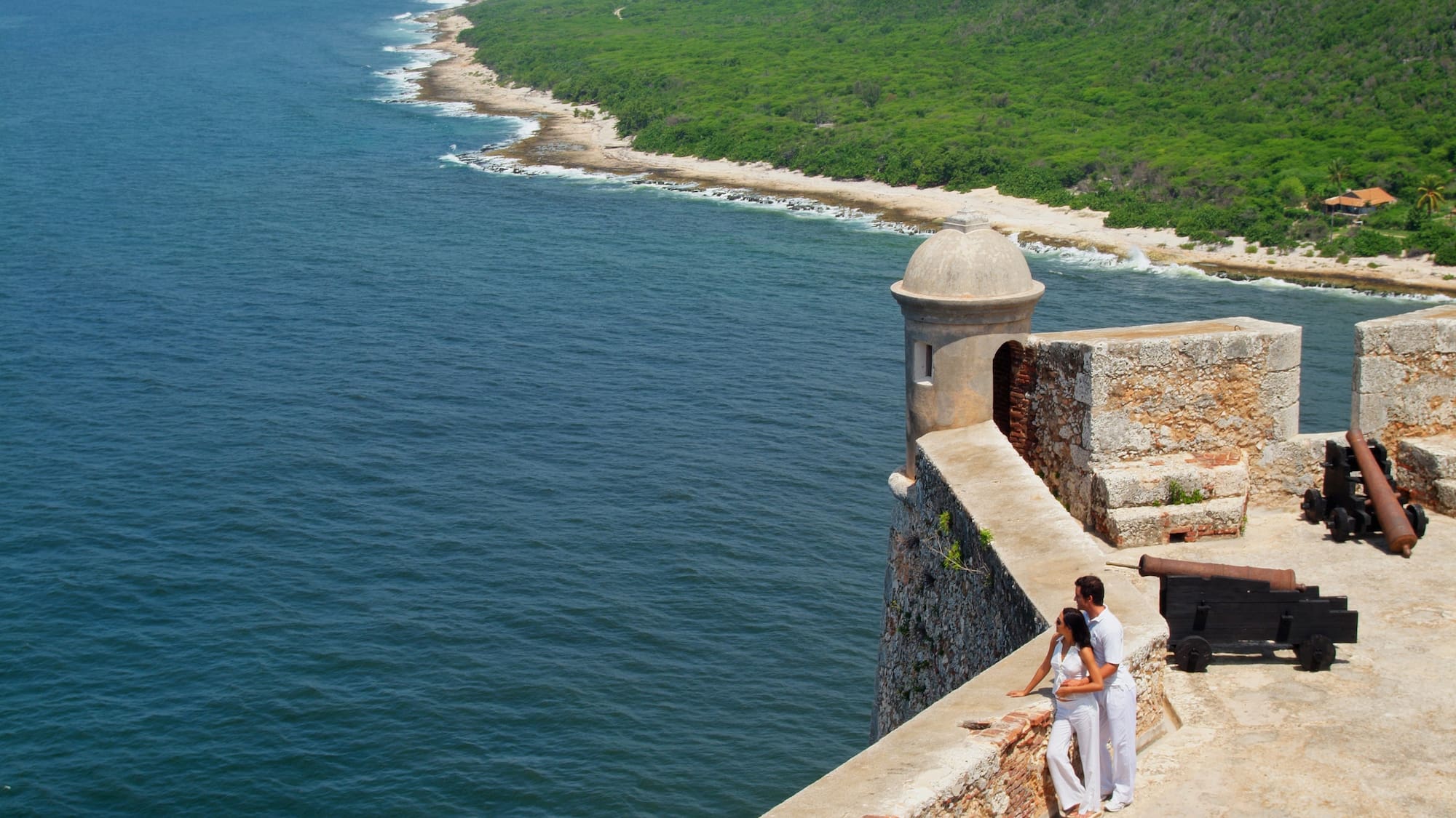 a man and woman standing on a wall overlooking a body of water
