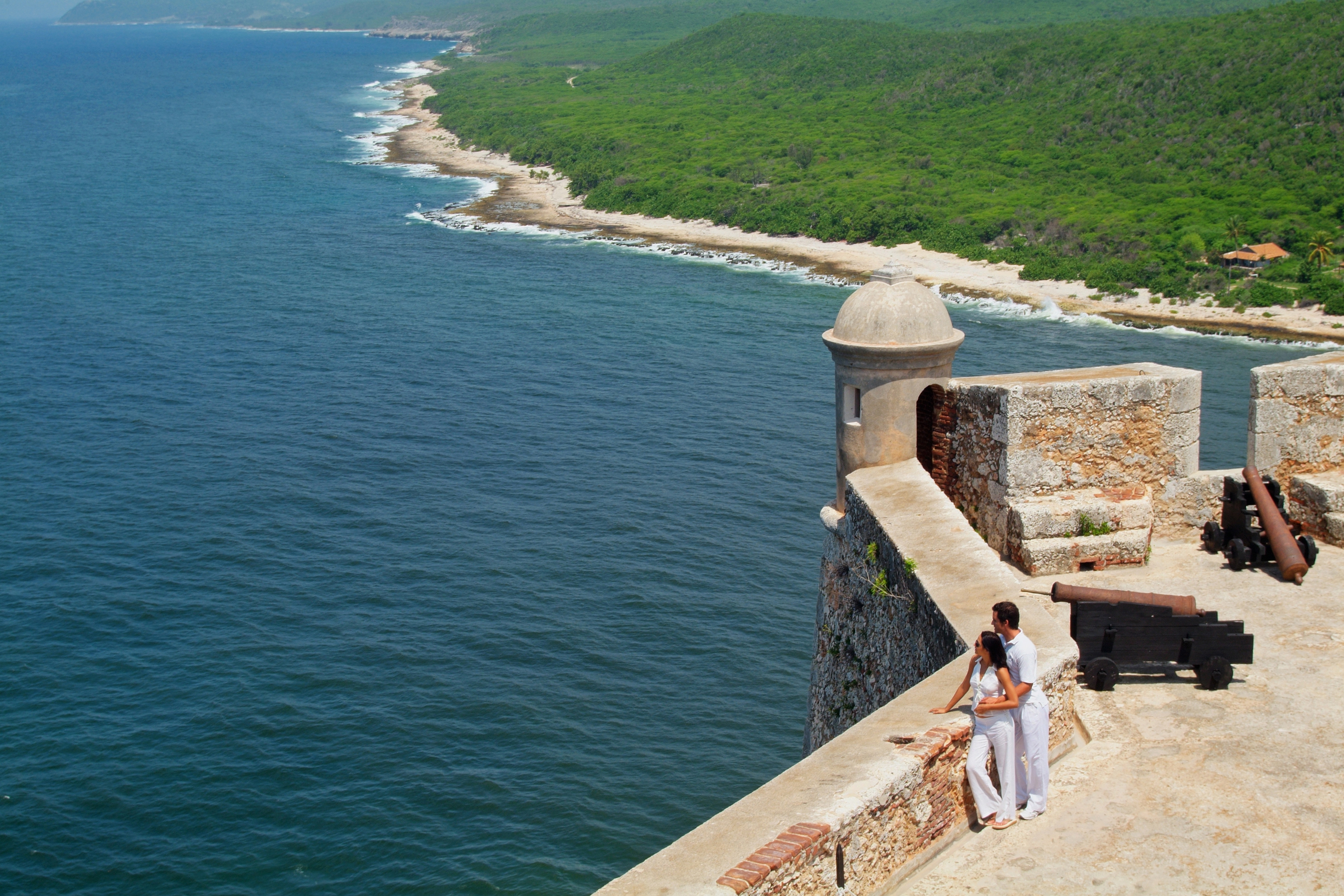 a man and woman standing on a wall overlooking a body of water