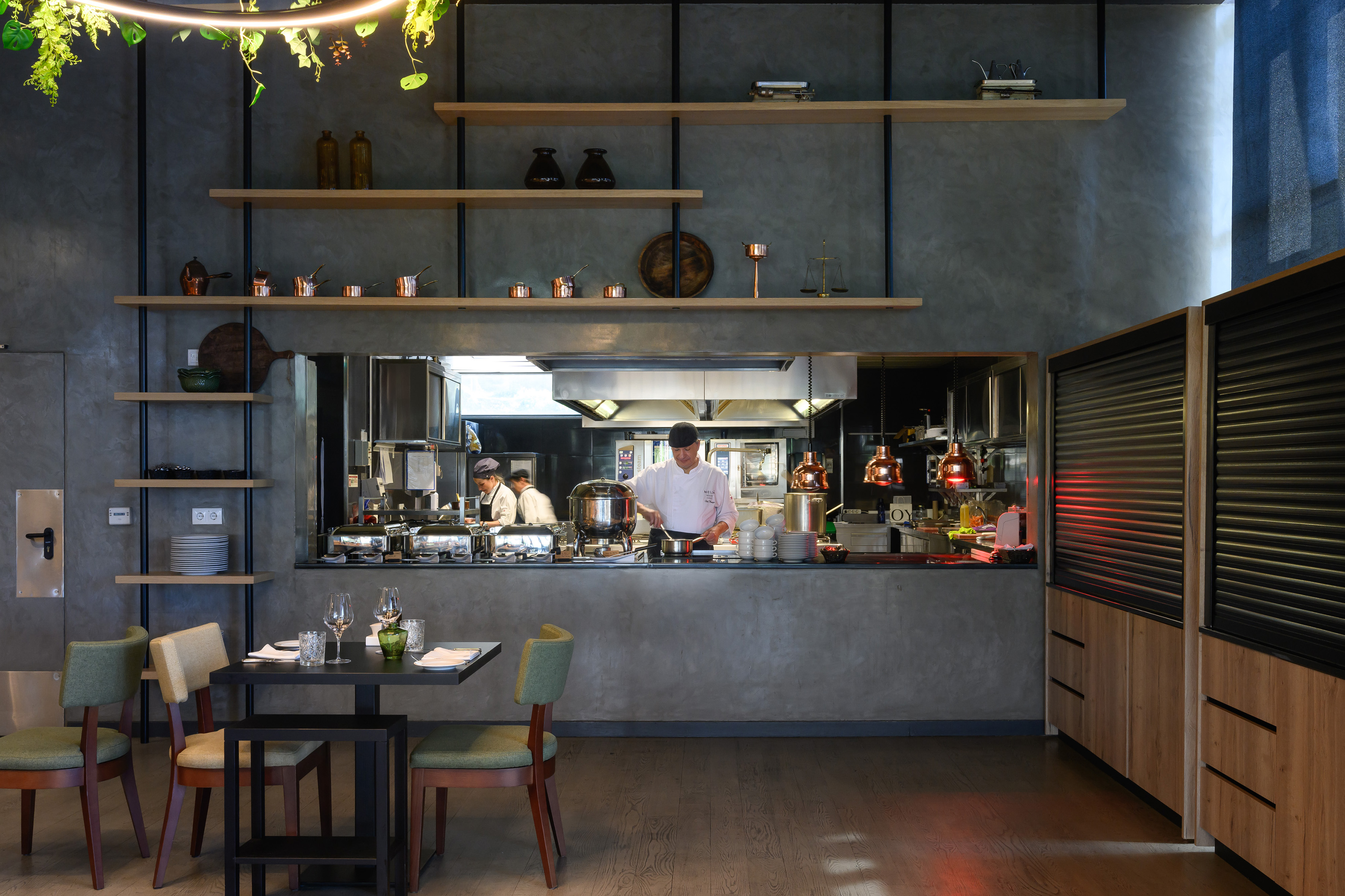 Chefs at work in a modern open-kitchen restaurant dining space.