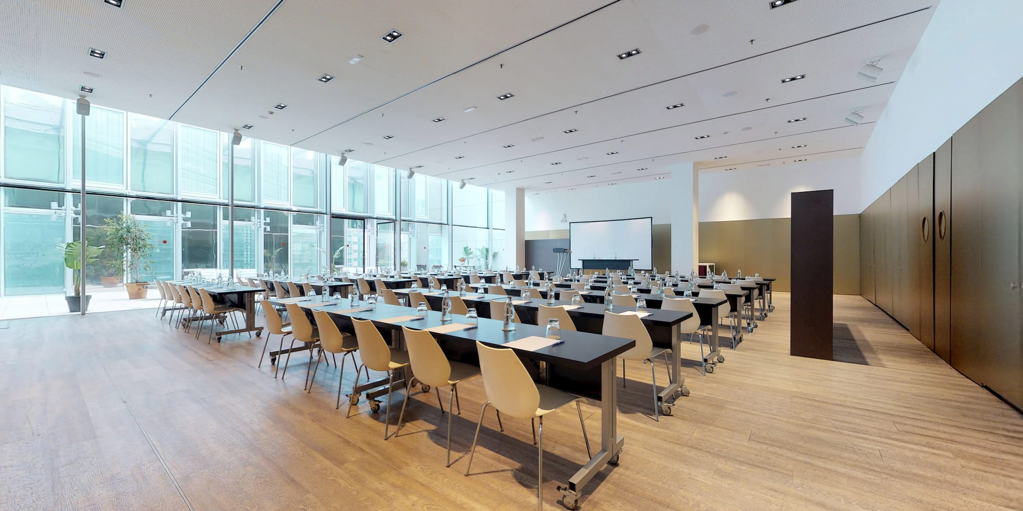Modern meeting room with projection screen, tables, and large windows.