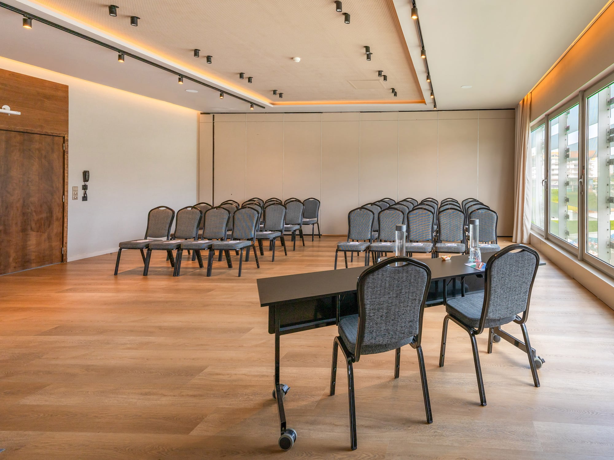 Modern empty conference room with chairs, tables, wood floor, and windows.