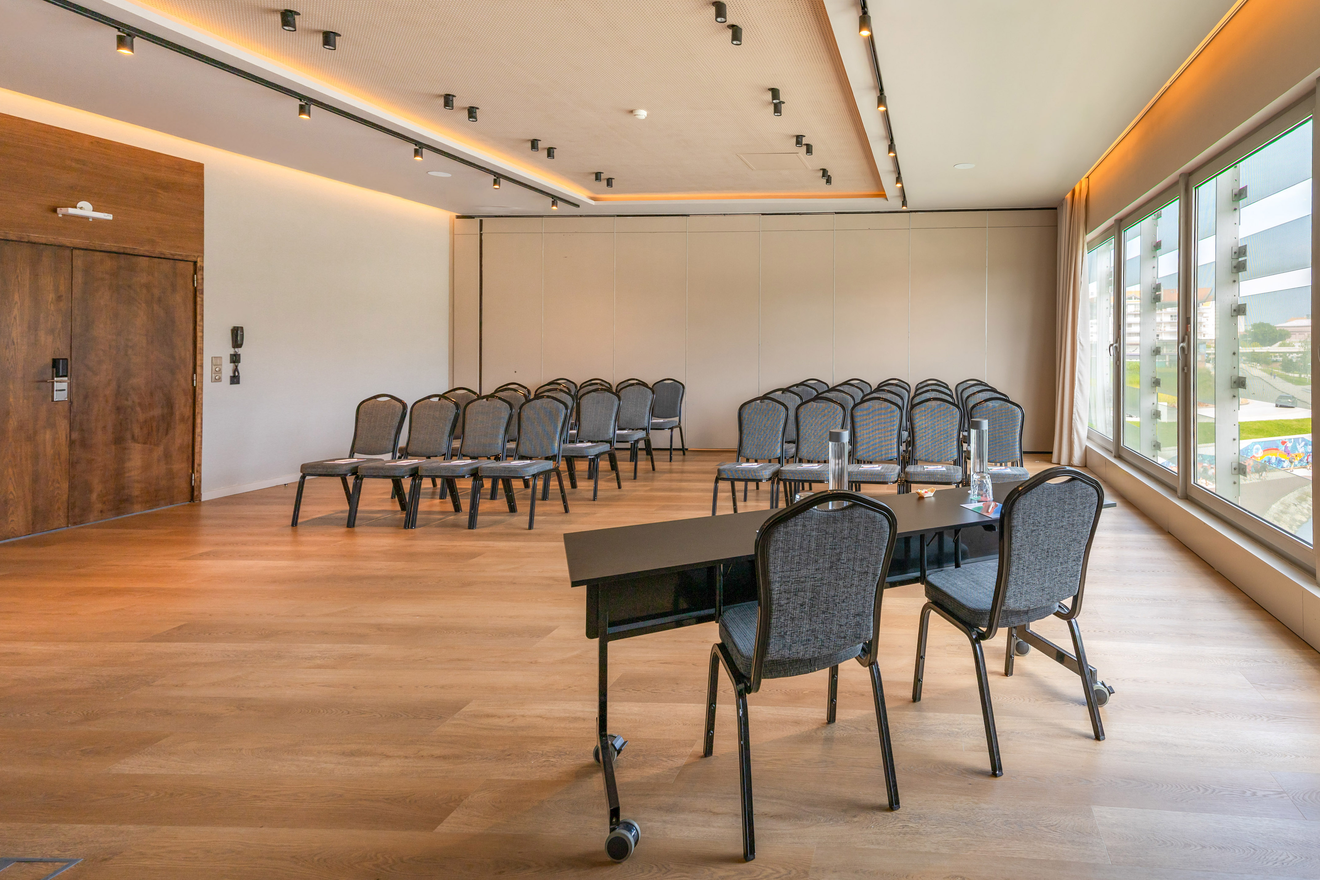 Modern empty conference room with chairs, tables, wood floor, and windows.