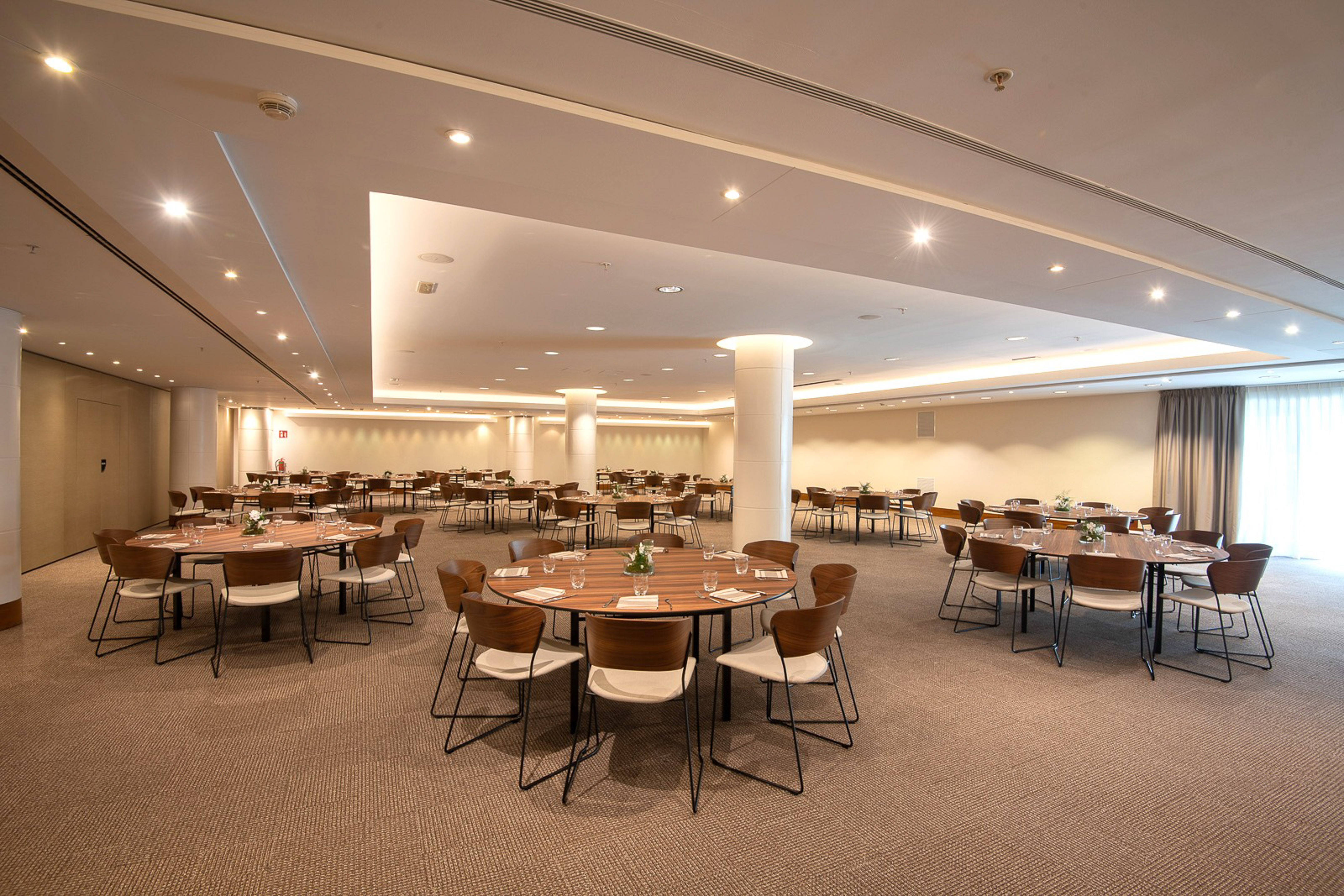 Spacious conference room with modern round tables and chairs, set for events.