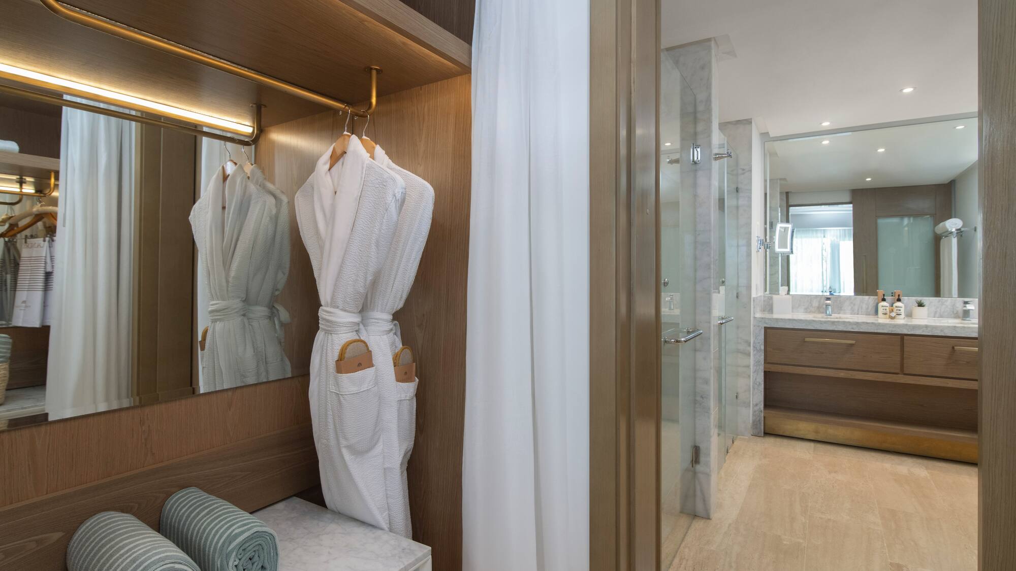 a bathroom with white bathrobes and towels