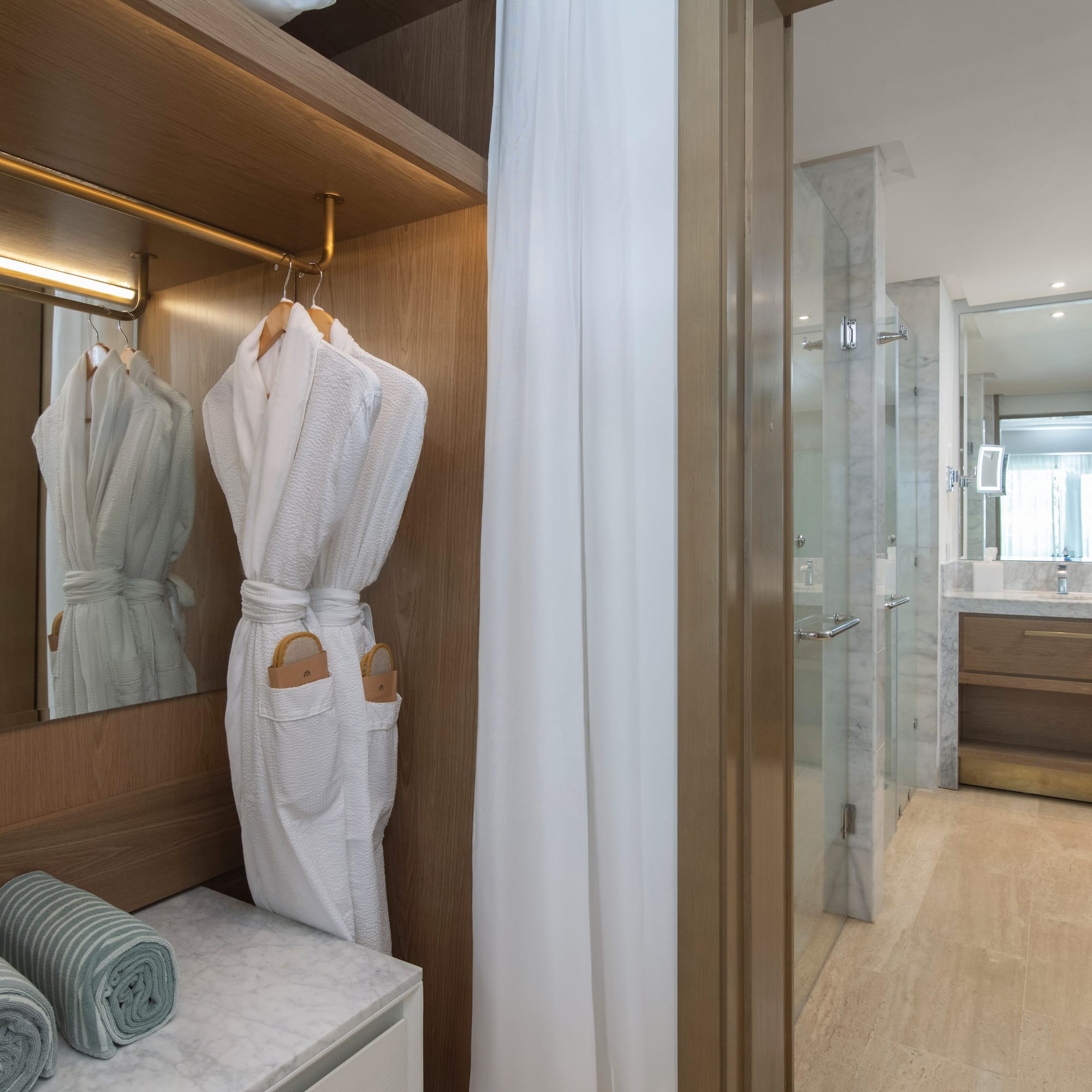a bathroom with white bathrobes and towels