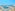 Hotel rooftop pool with ocean view, sunbeds, and outdoor tables.