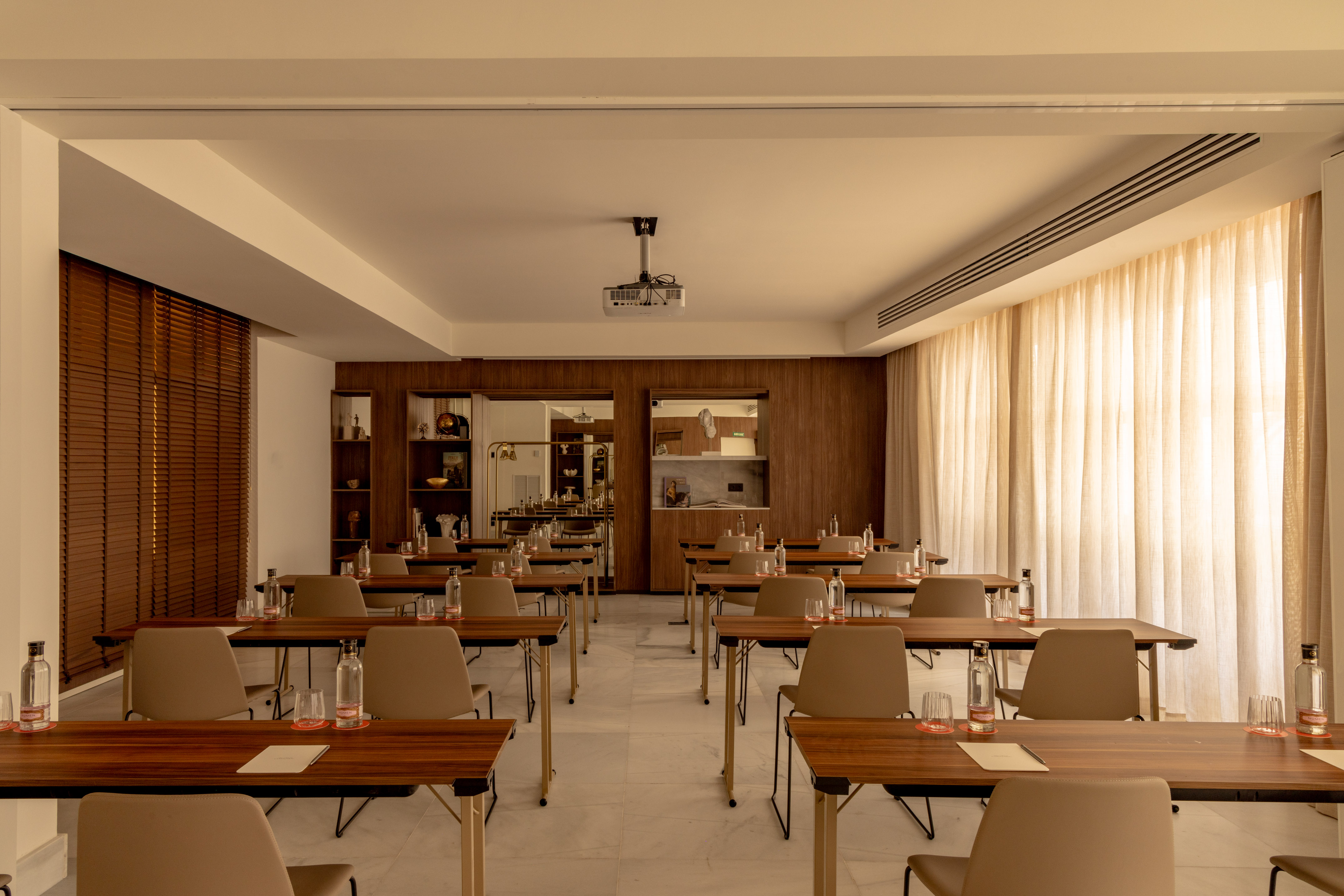 Modern meeting room with classroom setup, tables, chairs, and projector.