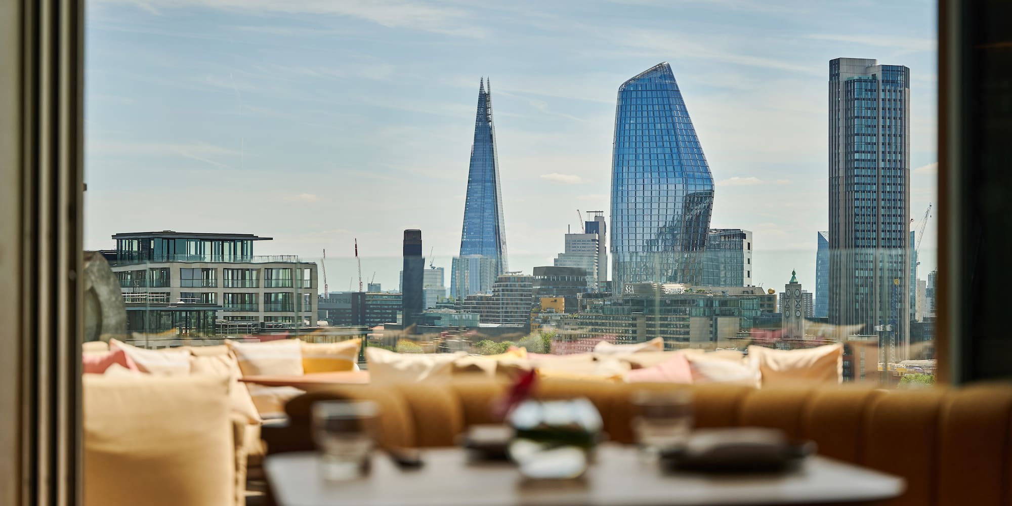 London skyline from a rooftop bar terrace, featuring The Shard and modern buildings.
