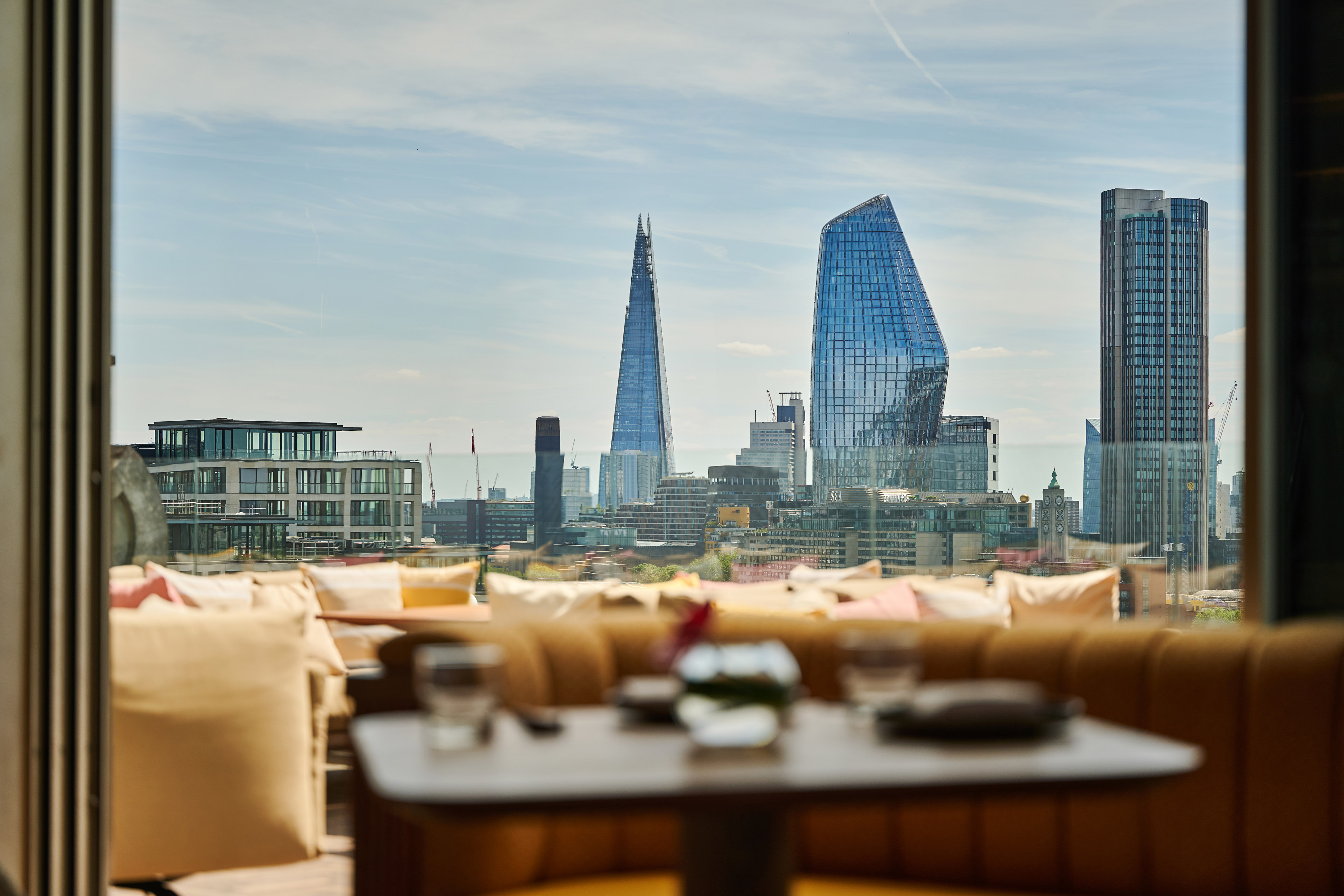 London skyline from a rooftop bar terrace, featuring The Shard and modern buildings.