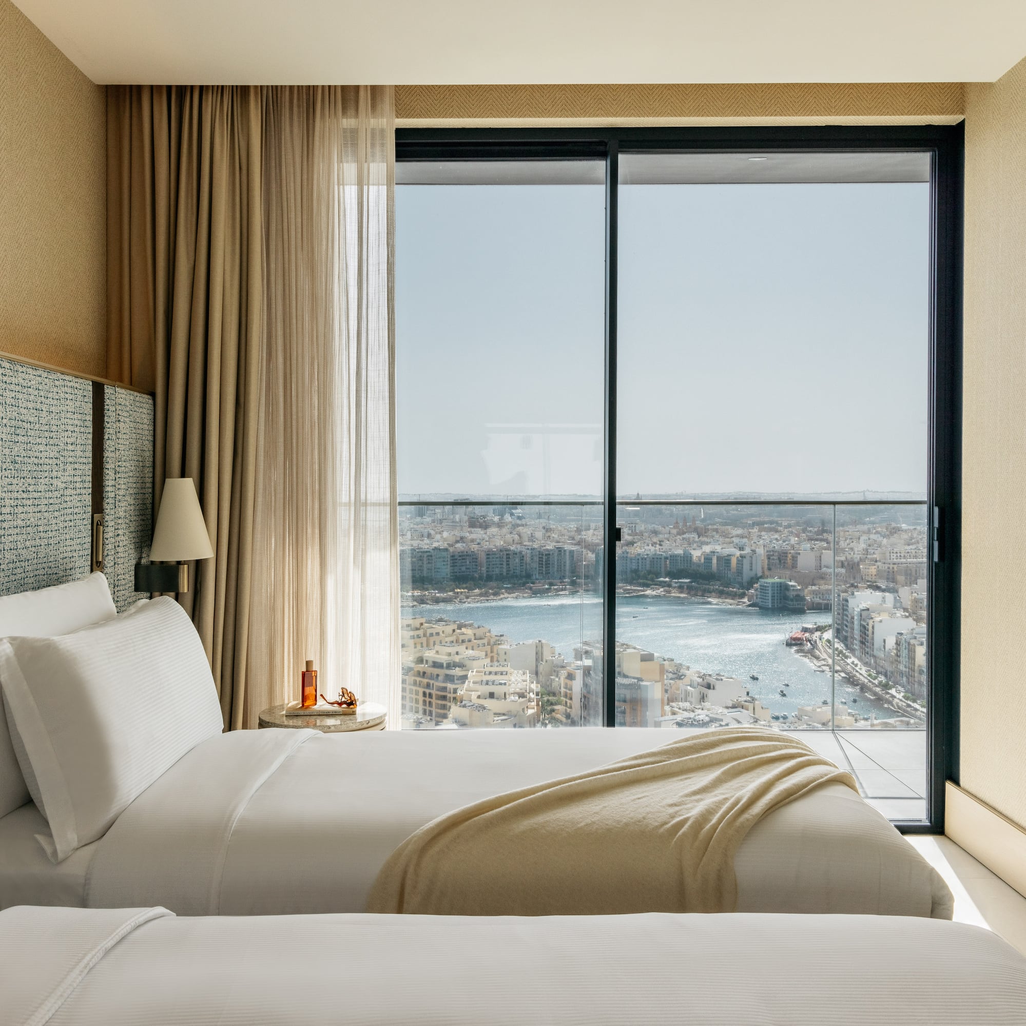 two beds in a room with a view of a city and a river