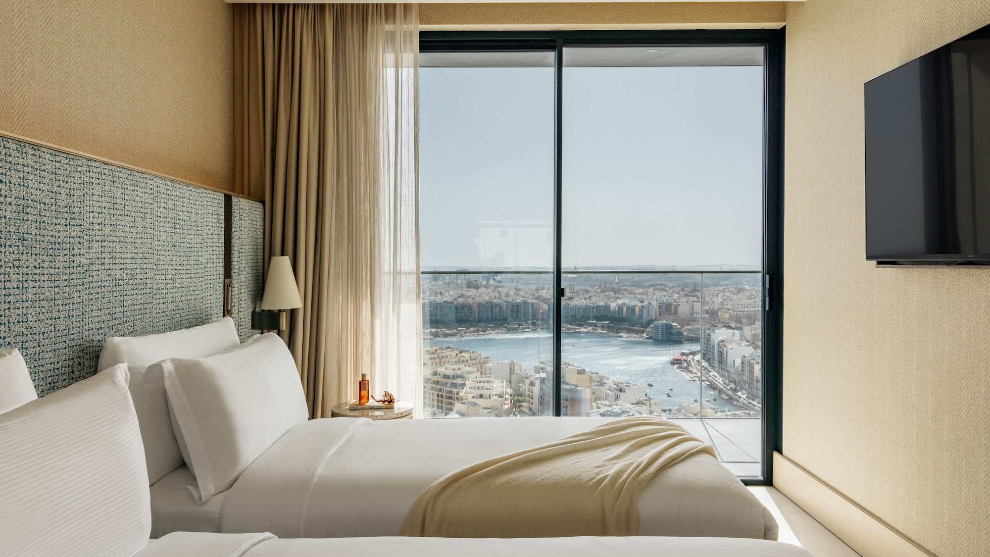 two beds in a room with a view of a city and a river
