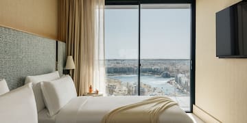 two beds in a room with a view of a city and a river