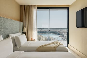 two beds in a room with a view of a city and a river