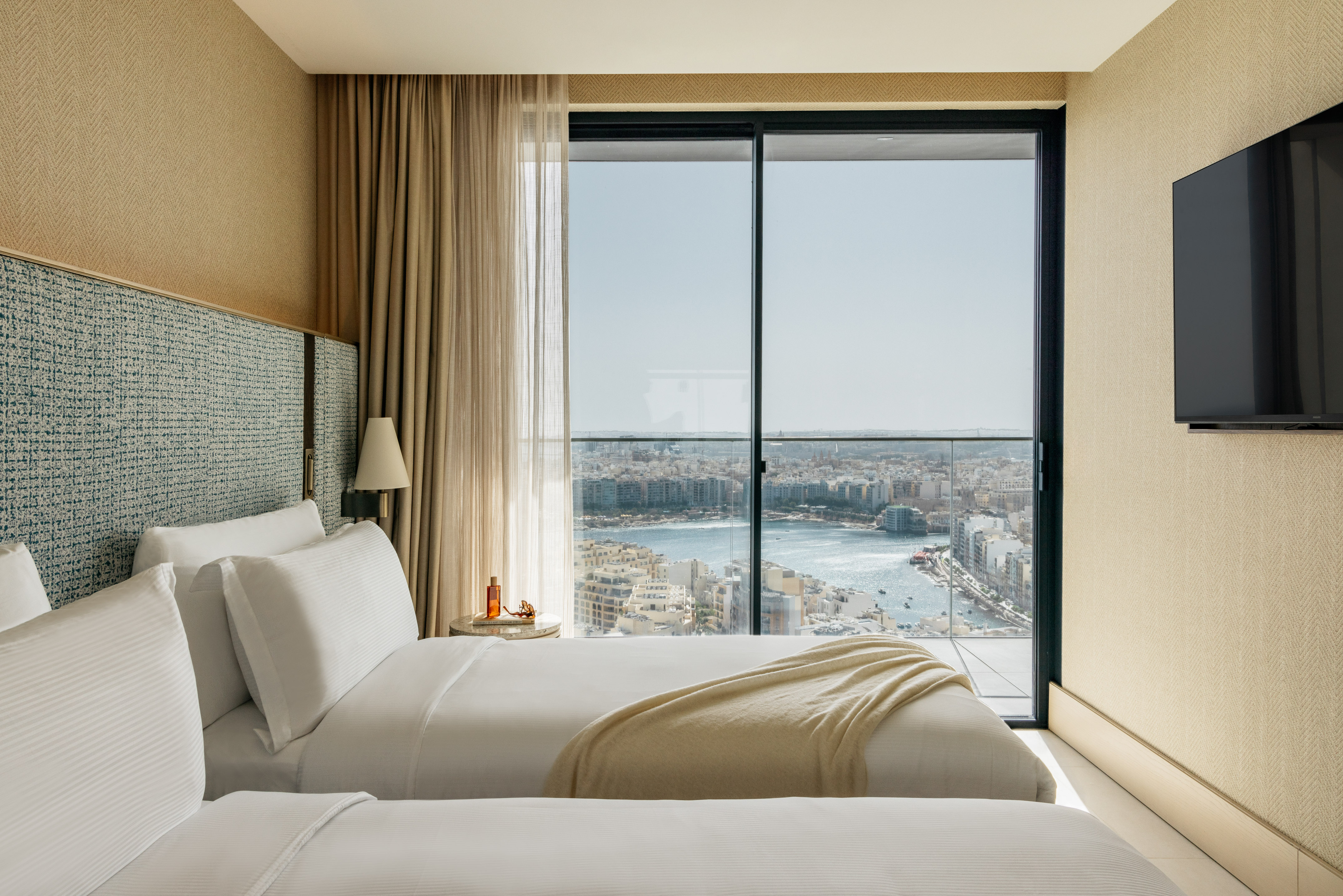two beds in a room with a view of a city and a river
