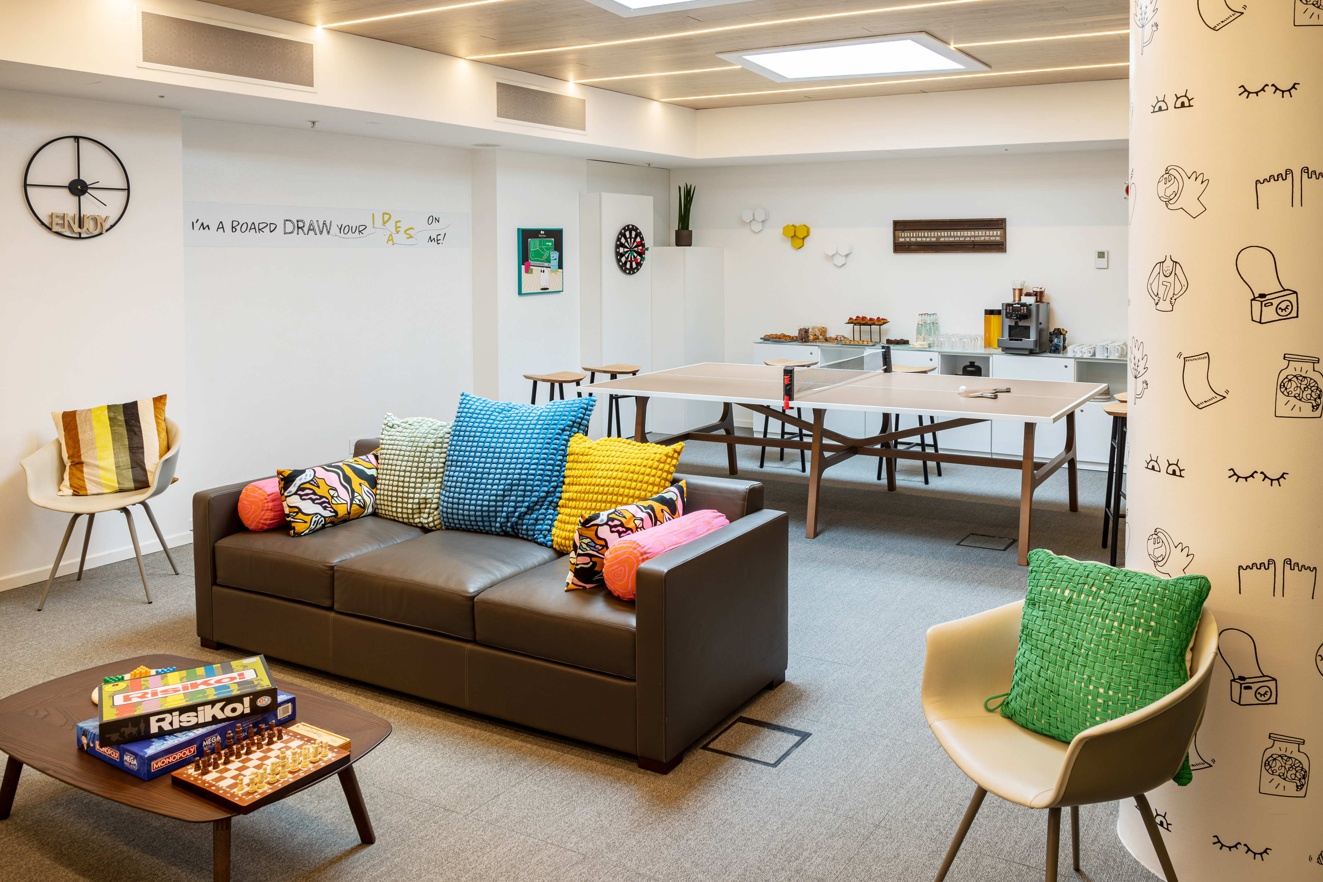 Office recreation space with sofa, board games, ping pong, and snack bar.