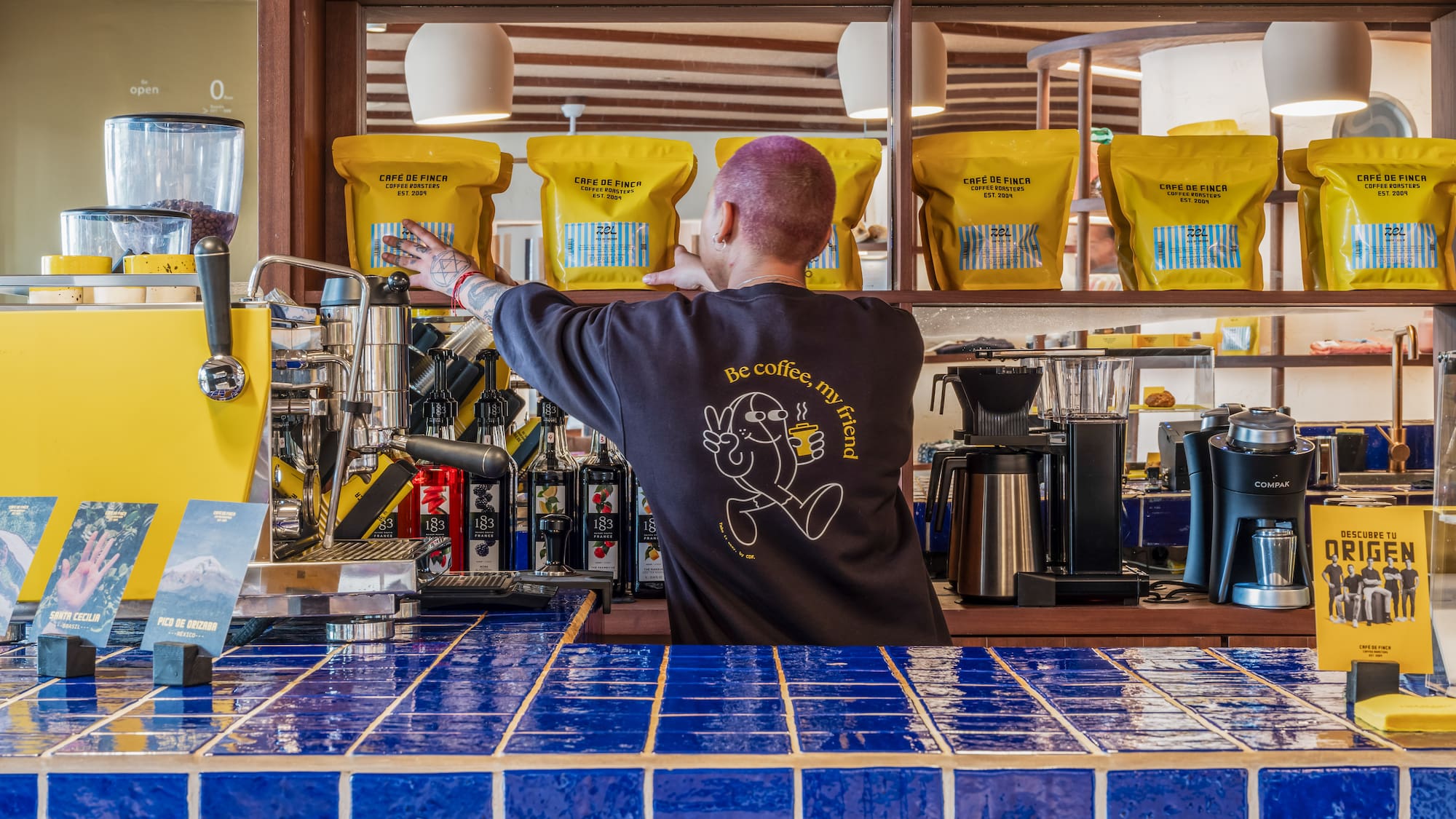 a man behind a counter with coffee machines