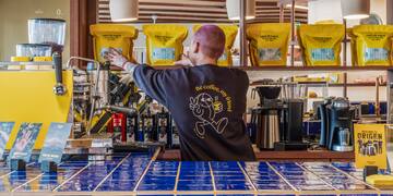 a man behind a counter with coffee machines