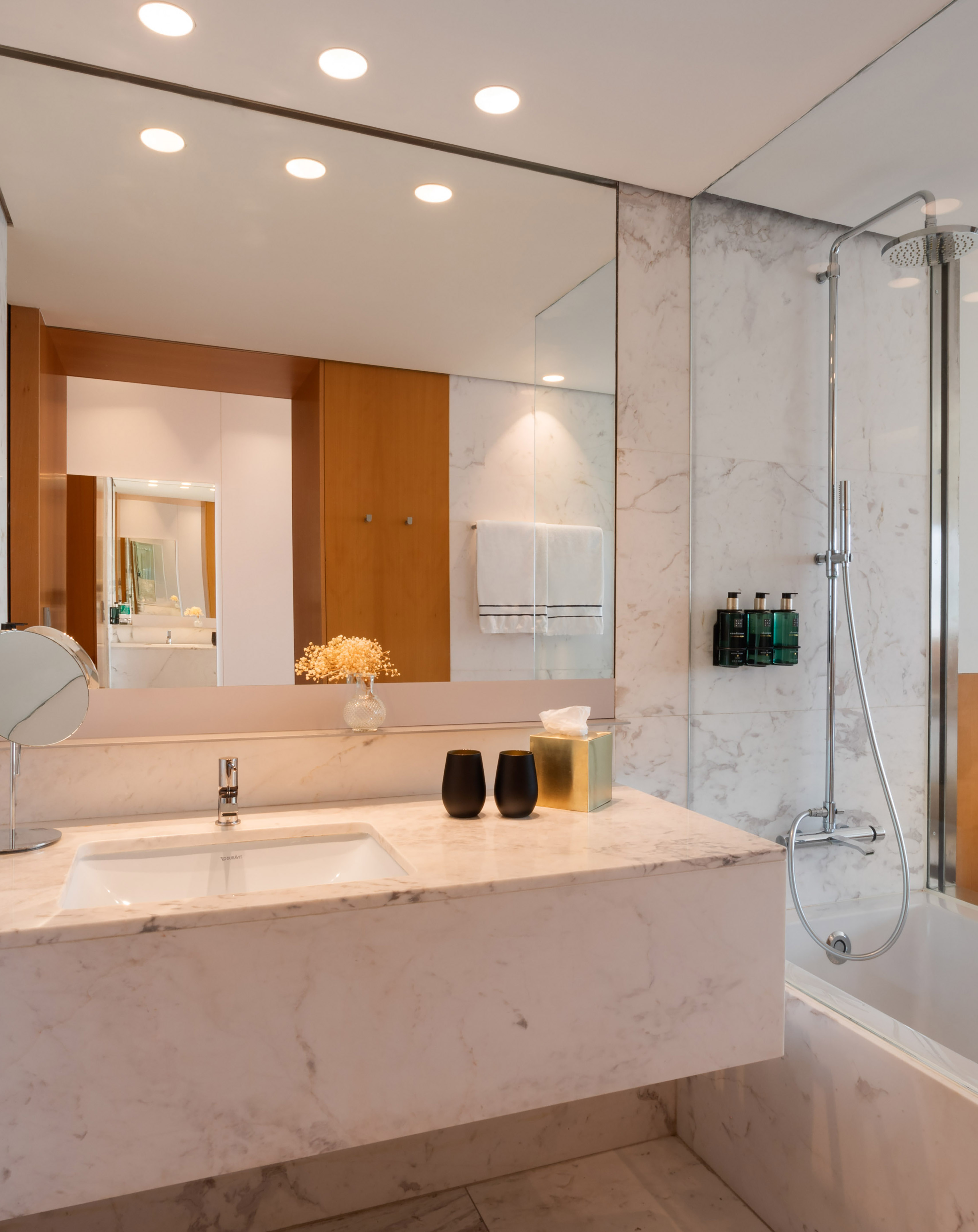 Modern bathroom with marble vanity, sink, large mirror, and shower-tub combo.