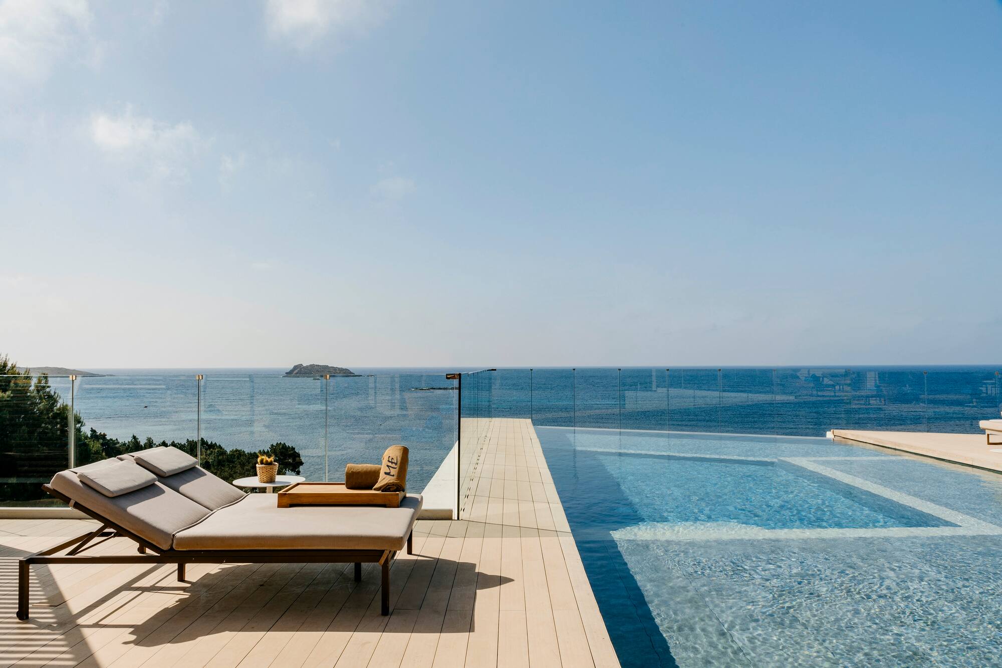 Luxury infinity pool with ocean view, lounge chair on modern deck.