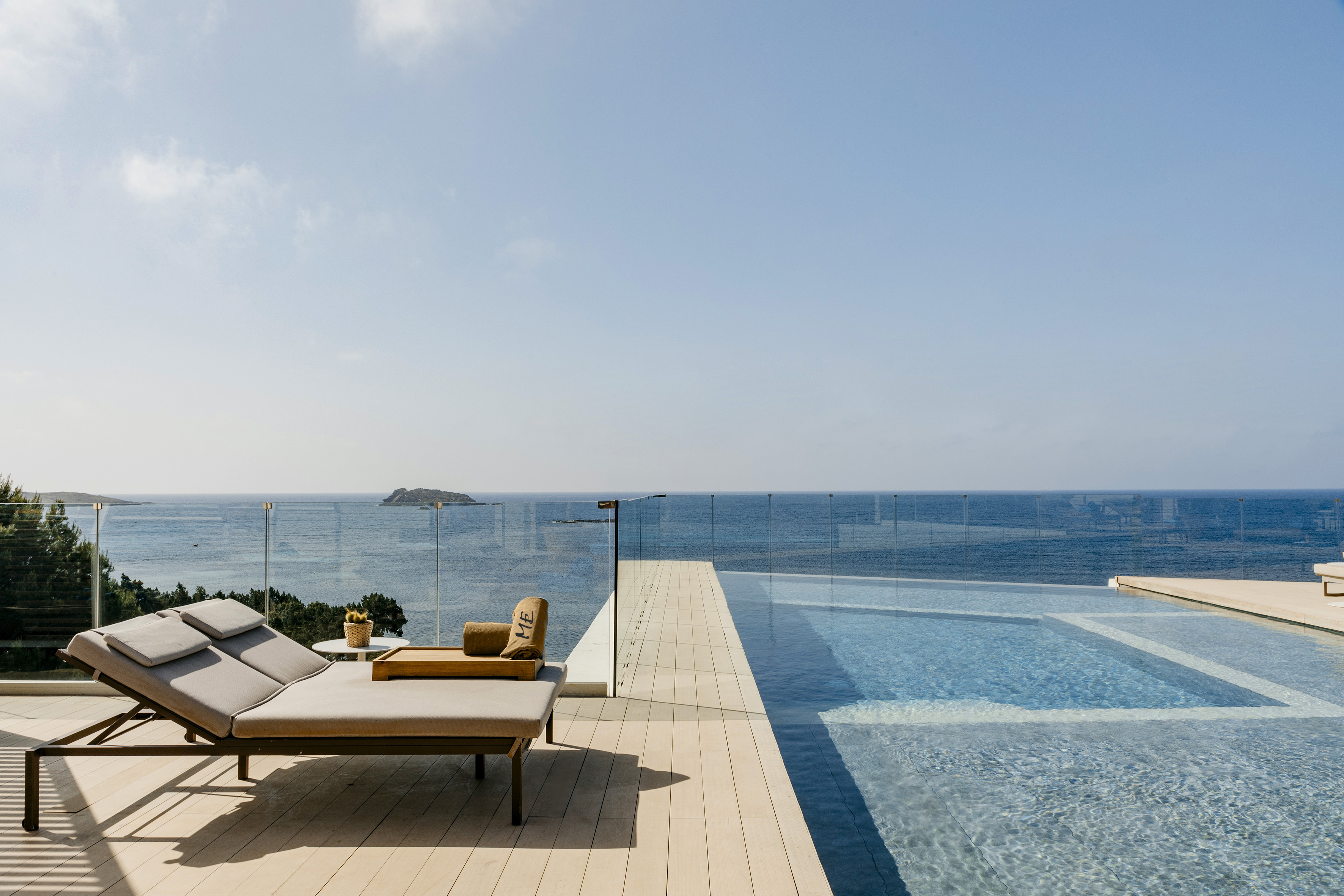 a pool with a deck chair and a glass fence