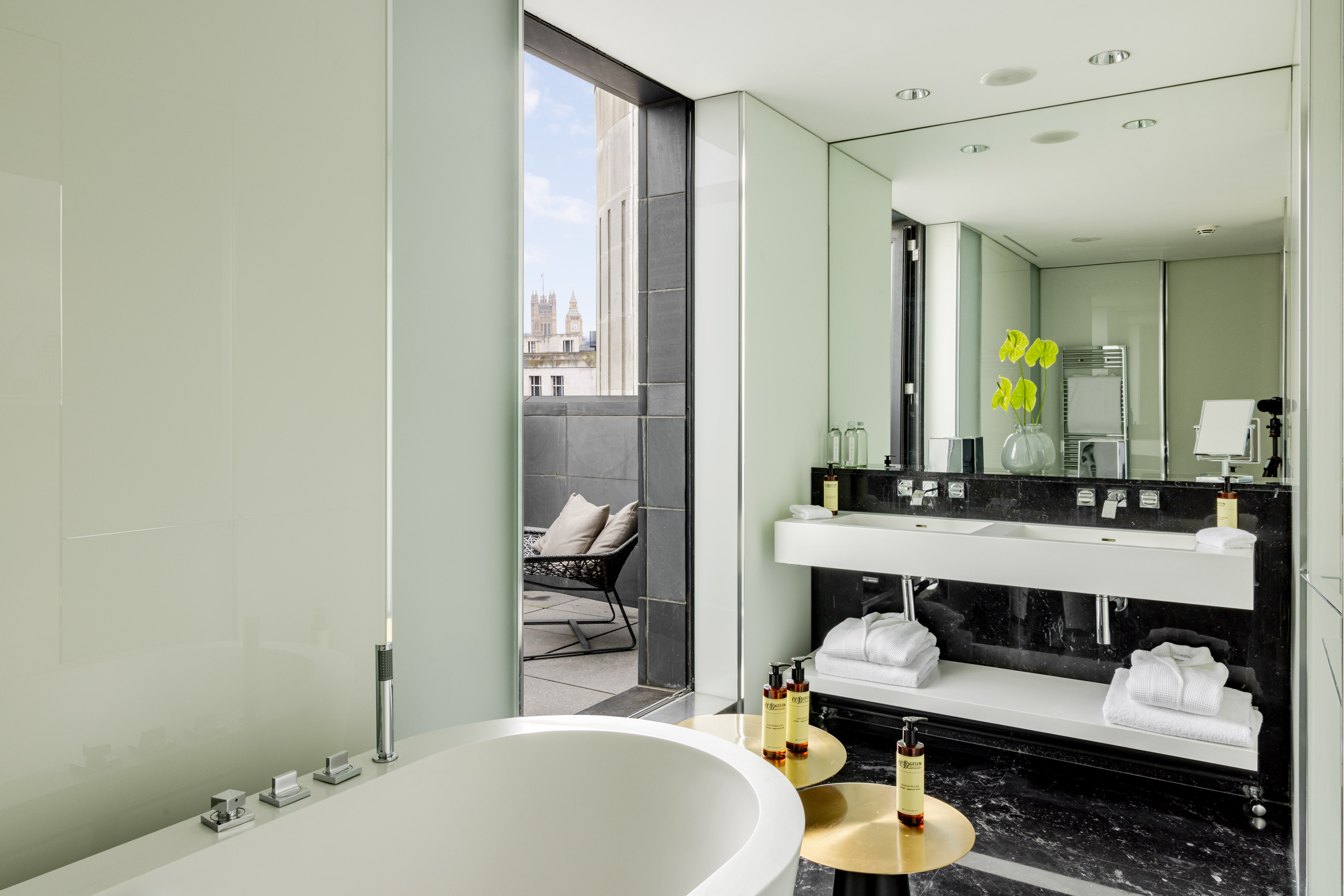 Chic hotel bathroom, freestanding tub, dual vanity, London skyline balcony.