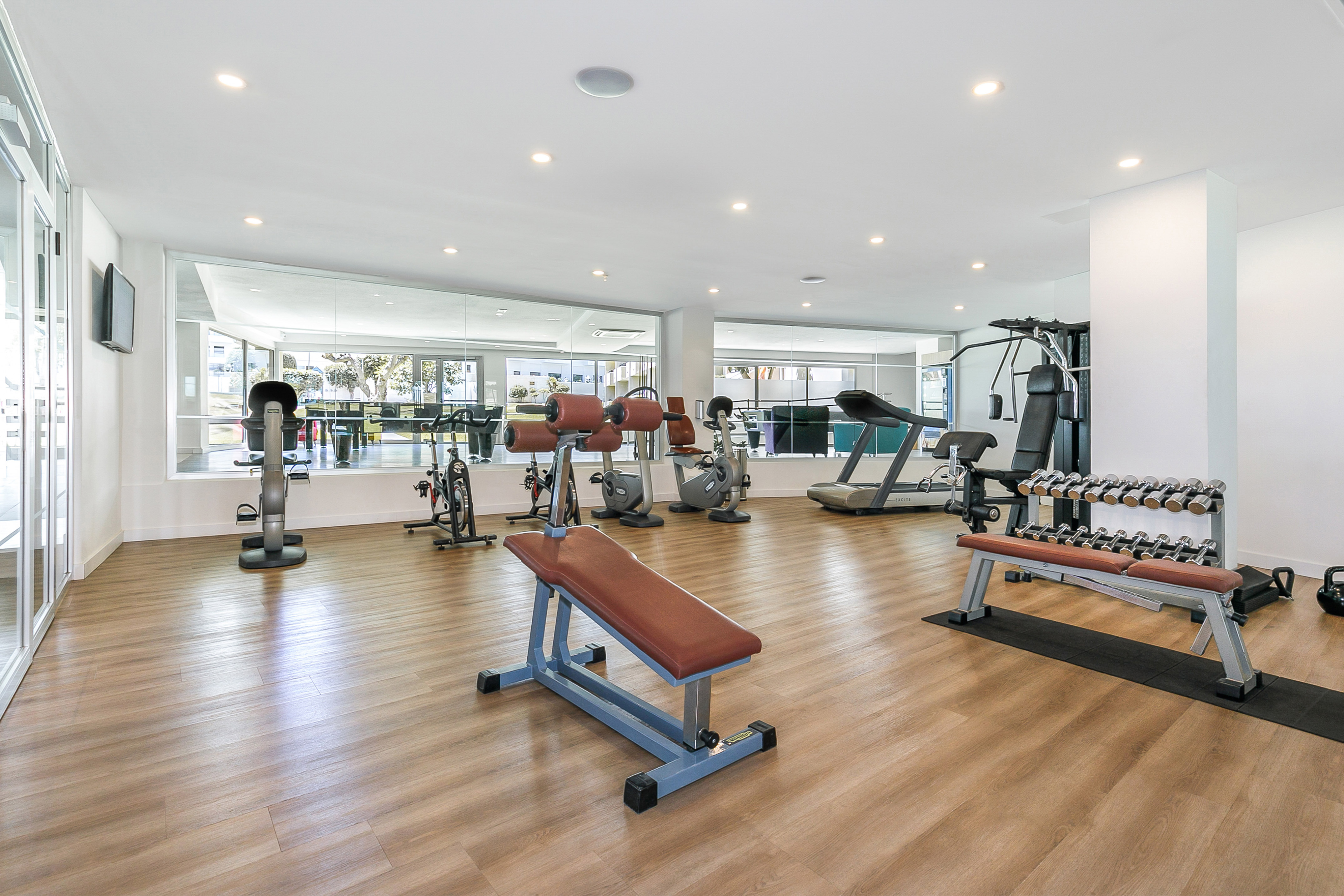 Bright modern gym with treadmills, exercise bikes, weights, and mirrors.