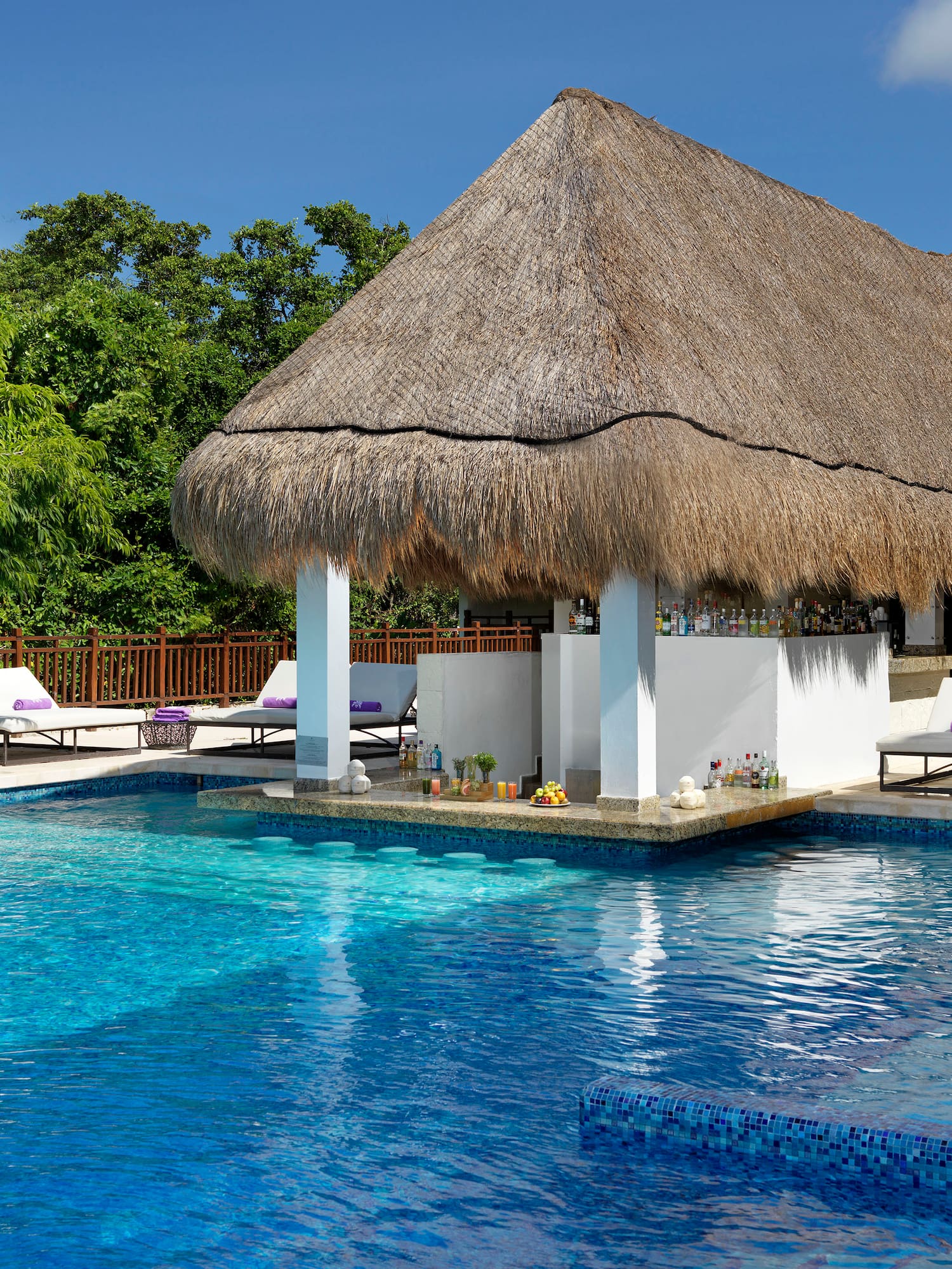 a pool with a thatched roof and lounge chairs