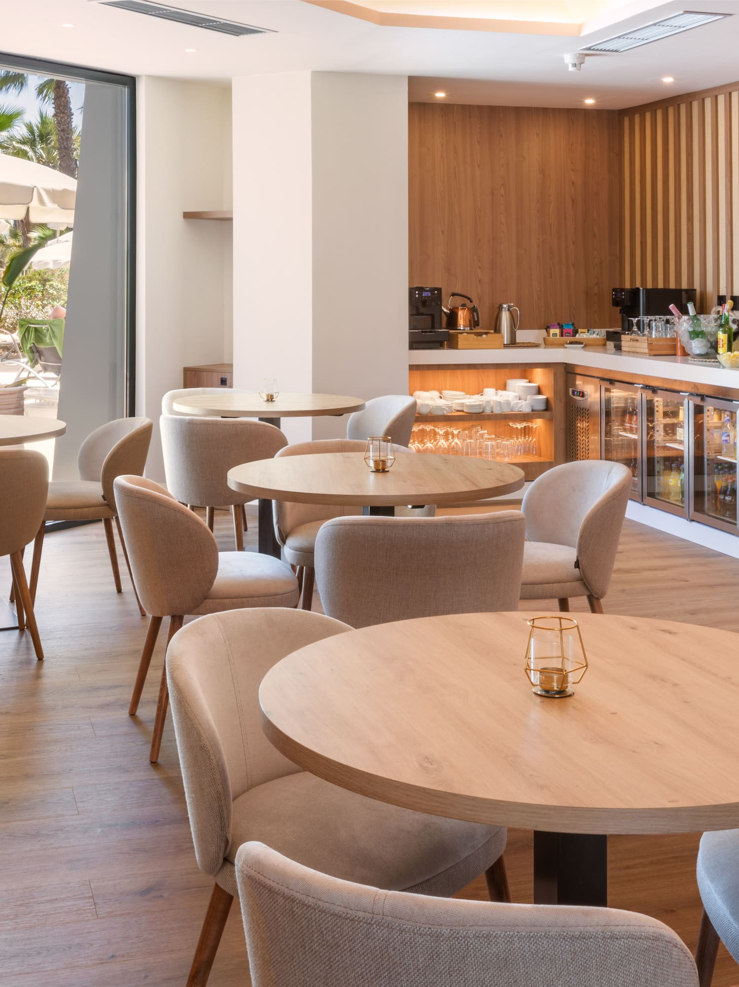 Contemporary hotel lounge with buffet, seating, and lush outdoor patio view.