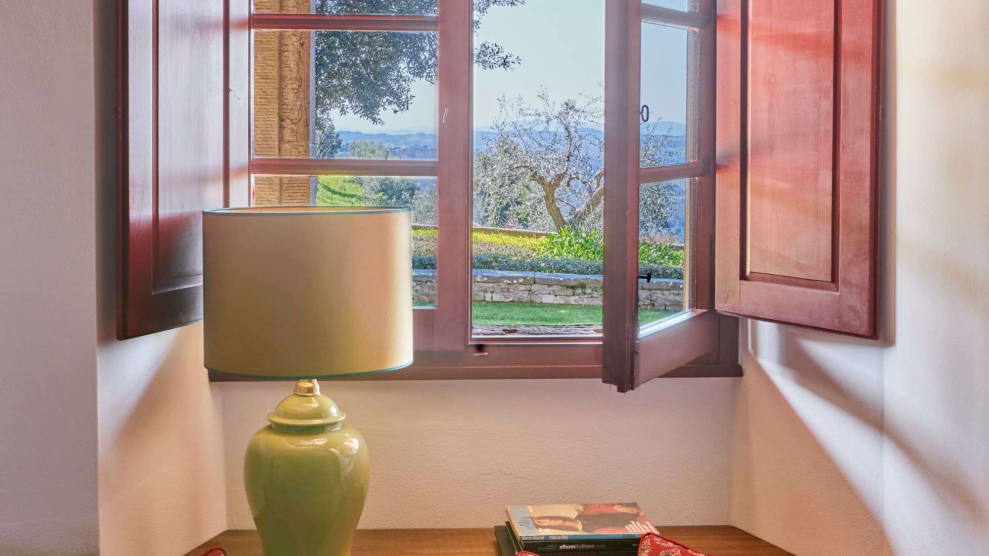 a window with open shutters and a couch with pillows