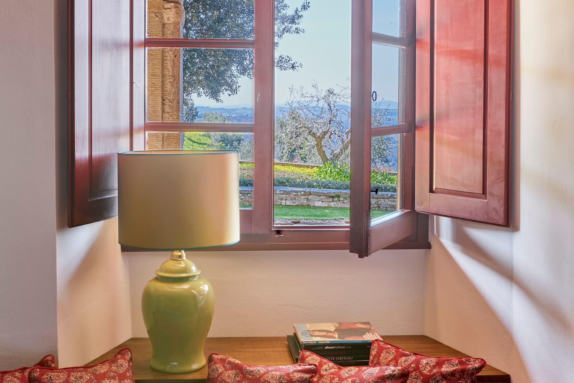 a window with open shutters and a couch with pillows