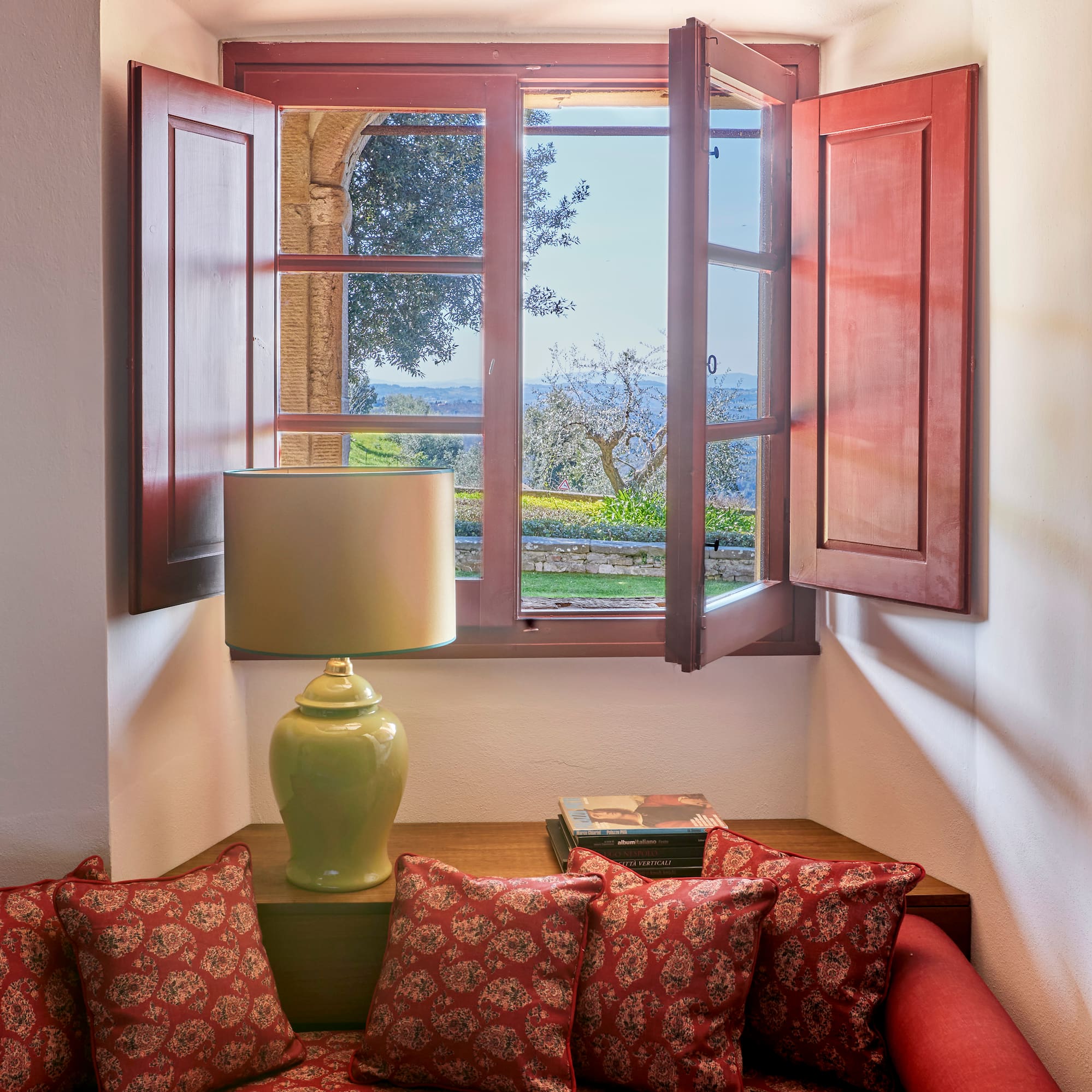 a window with open shutters and a couch with pillows