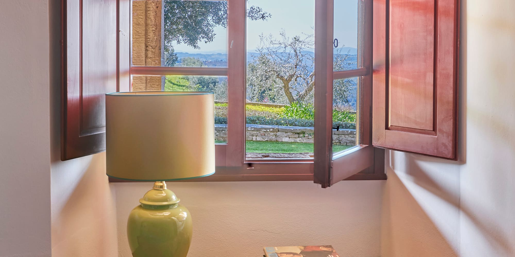 a window with open shutters and a couch with pillows