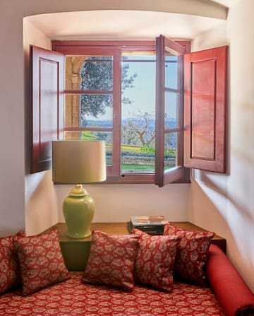 a window with open shutters and a couch with pillows