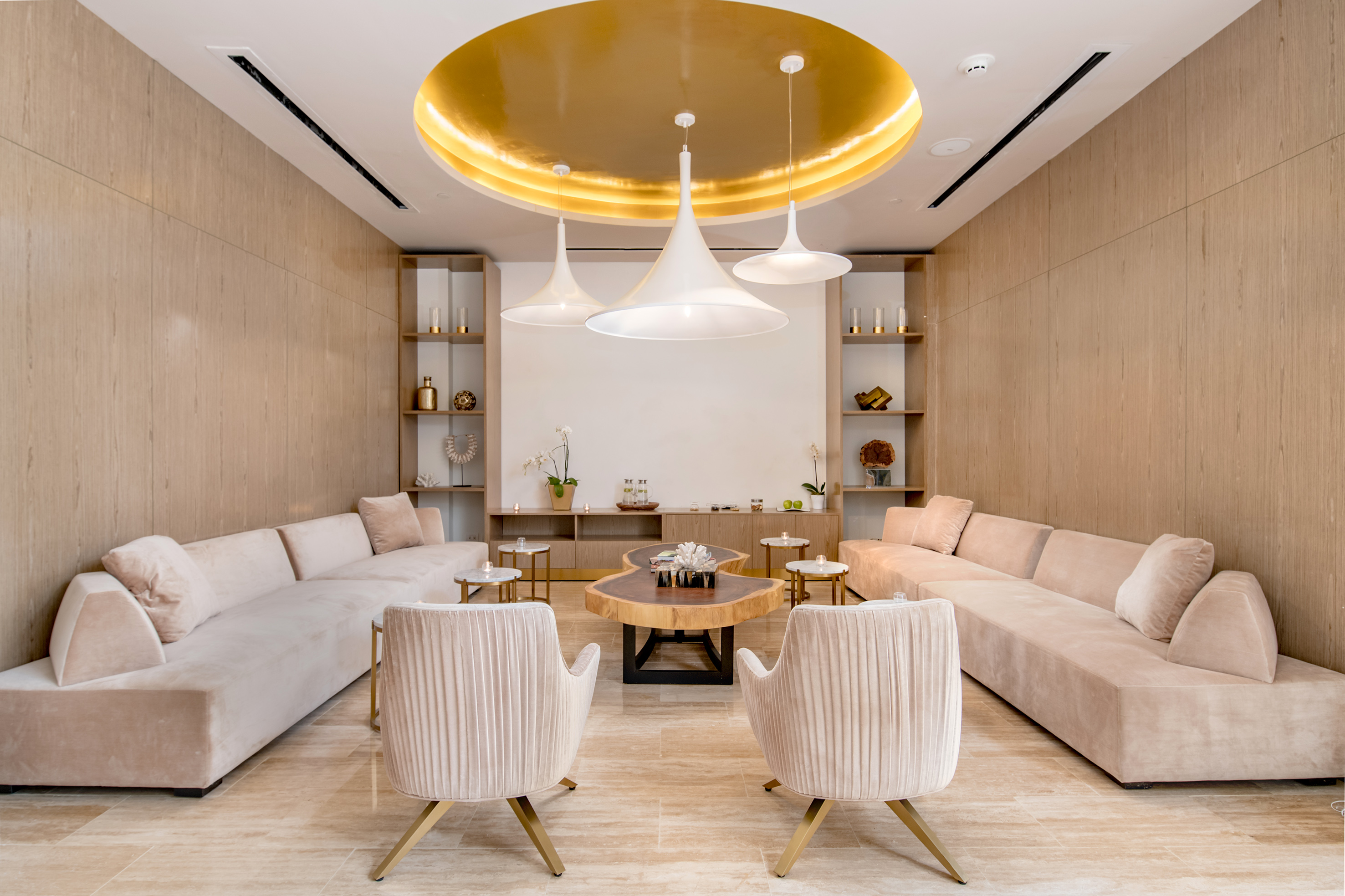 Modern lounge with pink sofas, wood walls, and golden ceiling.