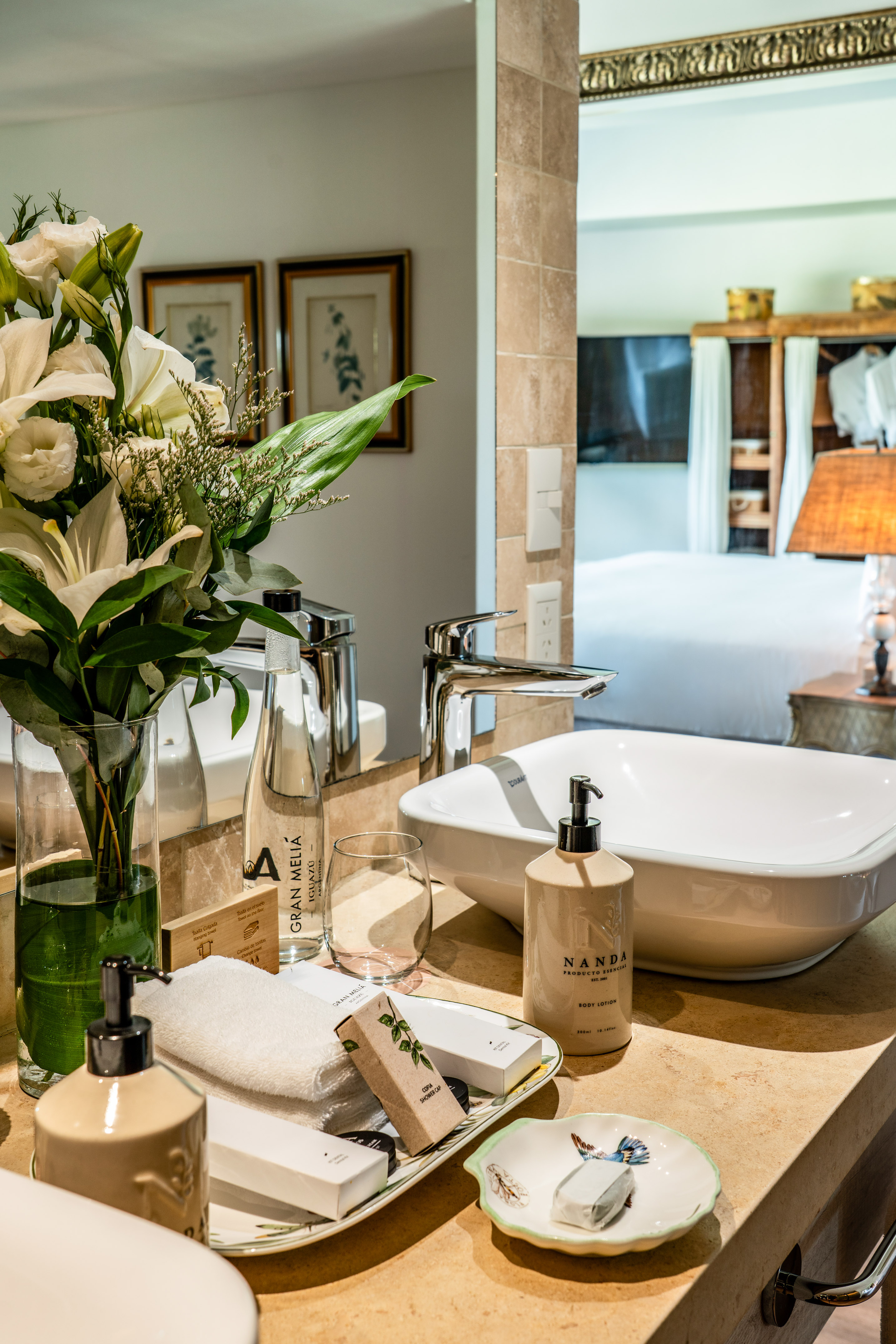 Luxury hotel bathroom vanity with white flowers, Gran Meliá toiletries, and sink.