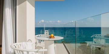 a table and chairs on a balcony overlooking the ocean