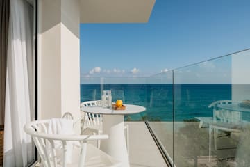 a table and chairs on a balcony overlooking the ocean
